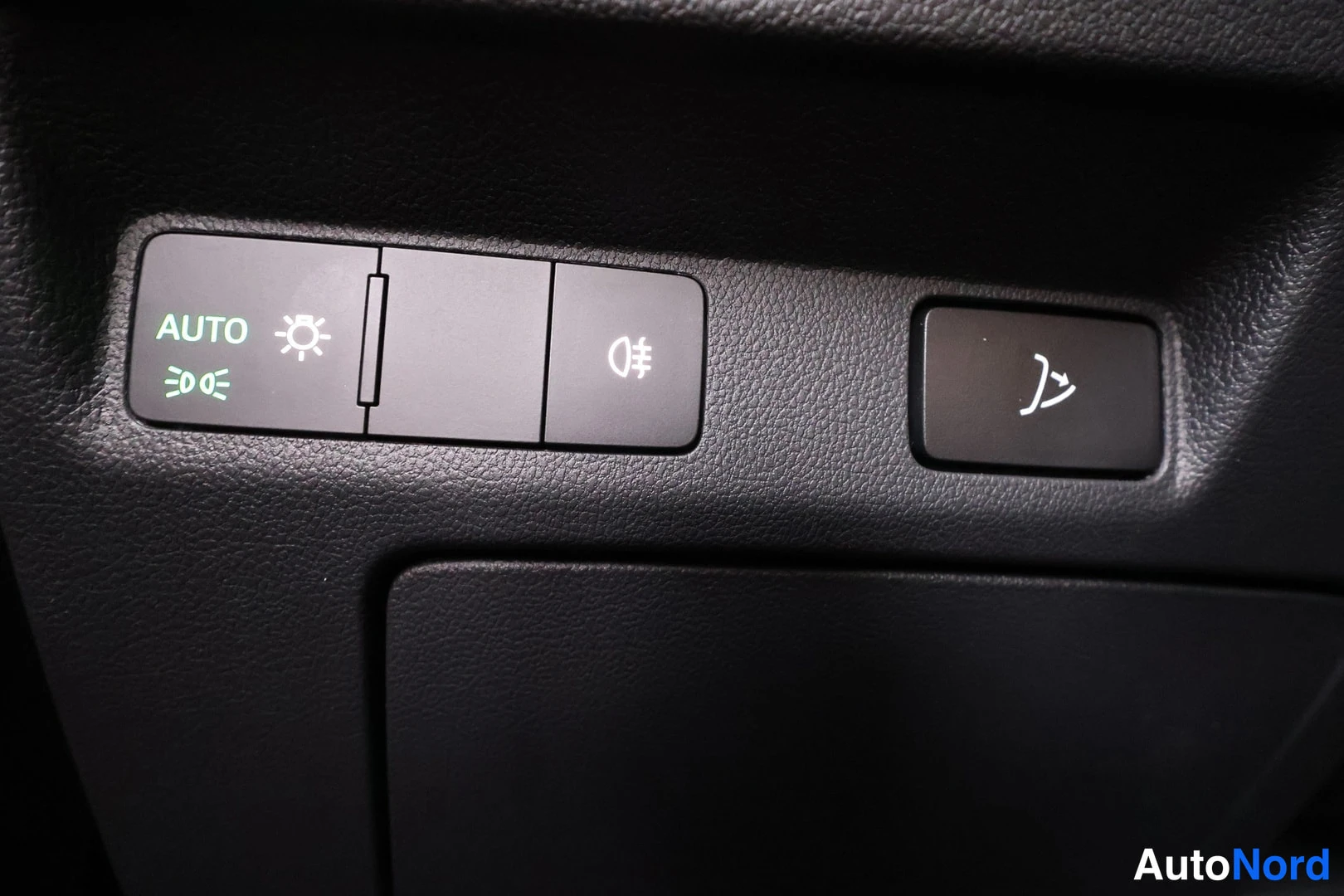 Muu: Sisätilakuvat: ajovalokytkin, jossa AUTO-merkintä ja valokuvioita, sekä erillinen nappi lämmintä puhaltaa symbolilla.