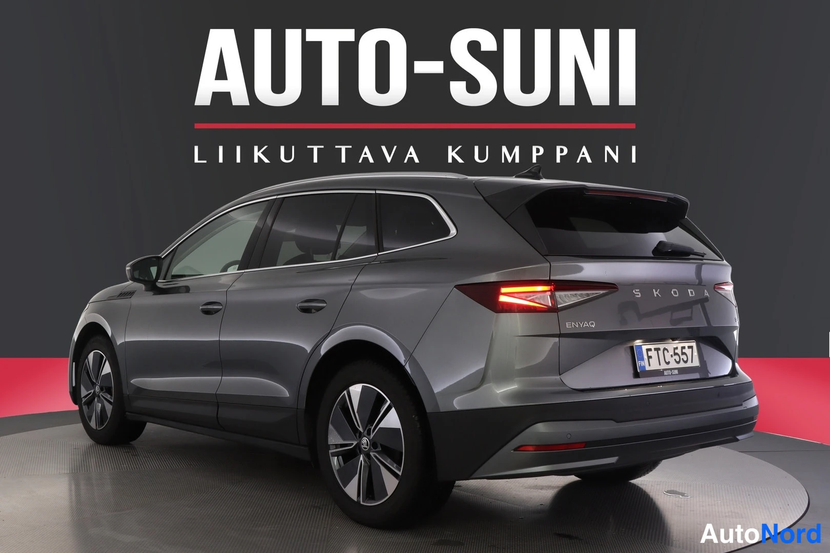 Takaviisto: Harmaan farmuriauton takakulma vasemmalta, Skoda Enyaq -tekstit takaluukussa ja rekennkyltti.