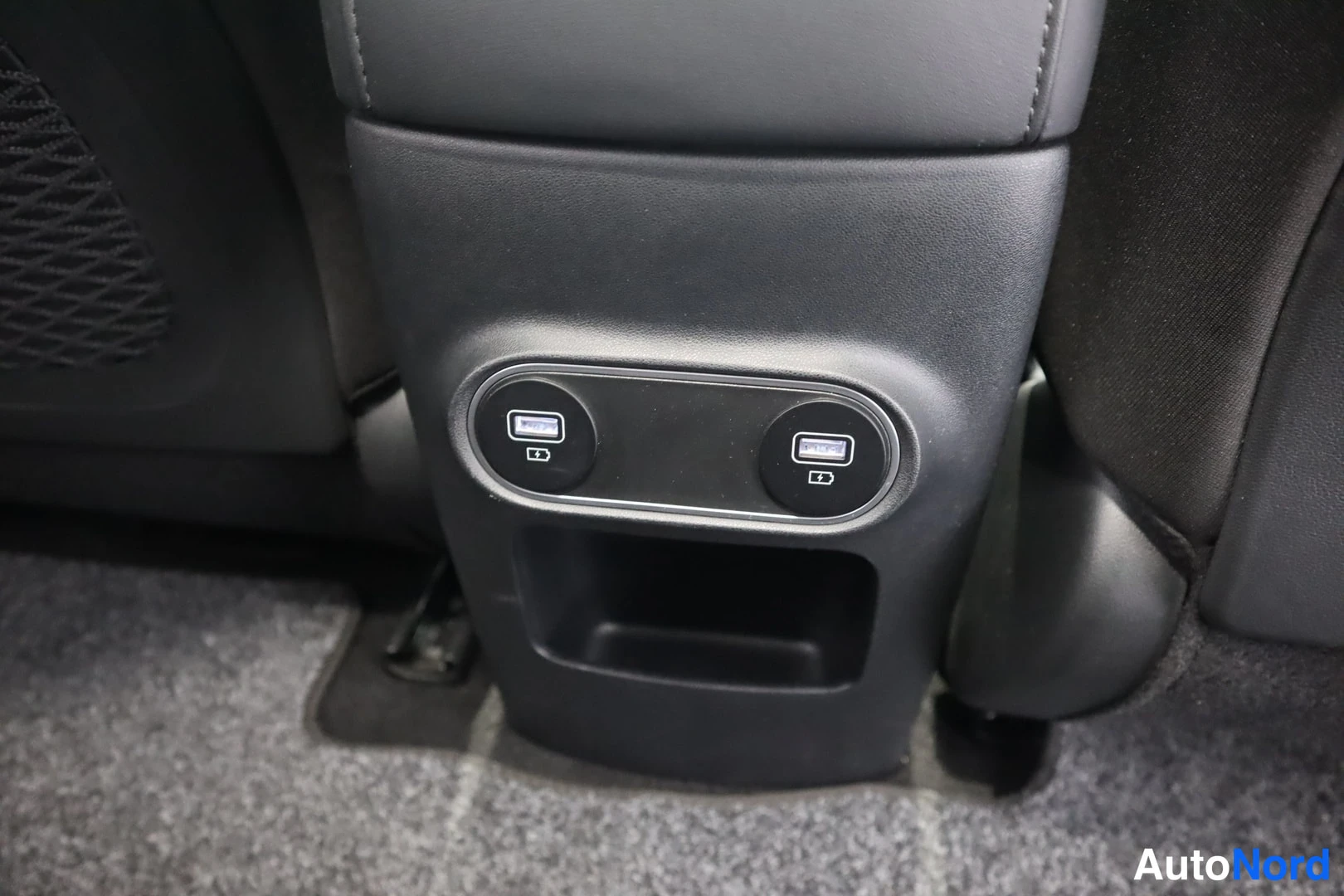 Sivulta: Etumatkustajan selkänojan takana oleva keskinainen konsoli, jossa kaksi USB-latausporttia ja säilytyslokero.