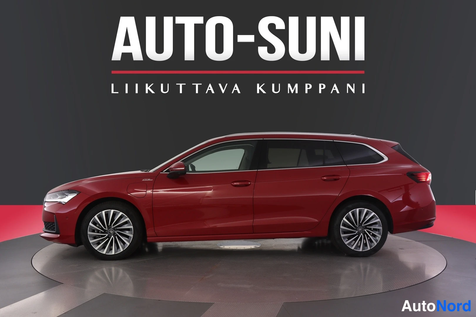 Sivulta: Punainen farmariauto sivulta kuvattuna studio-tyyppisessä tilassa, taustalla tumma seinä ja AUTO-SUNI-logoteksti.