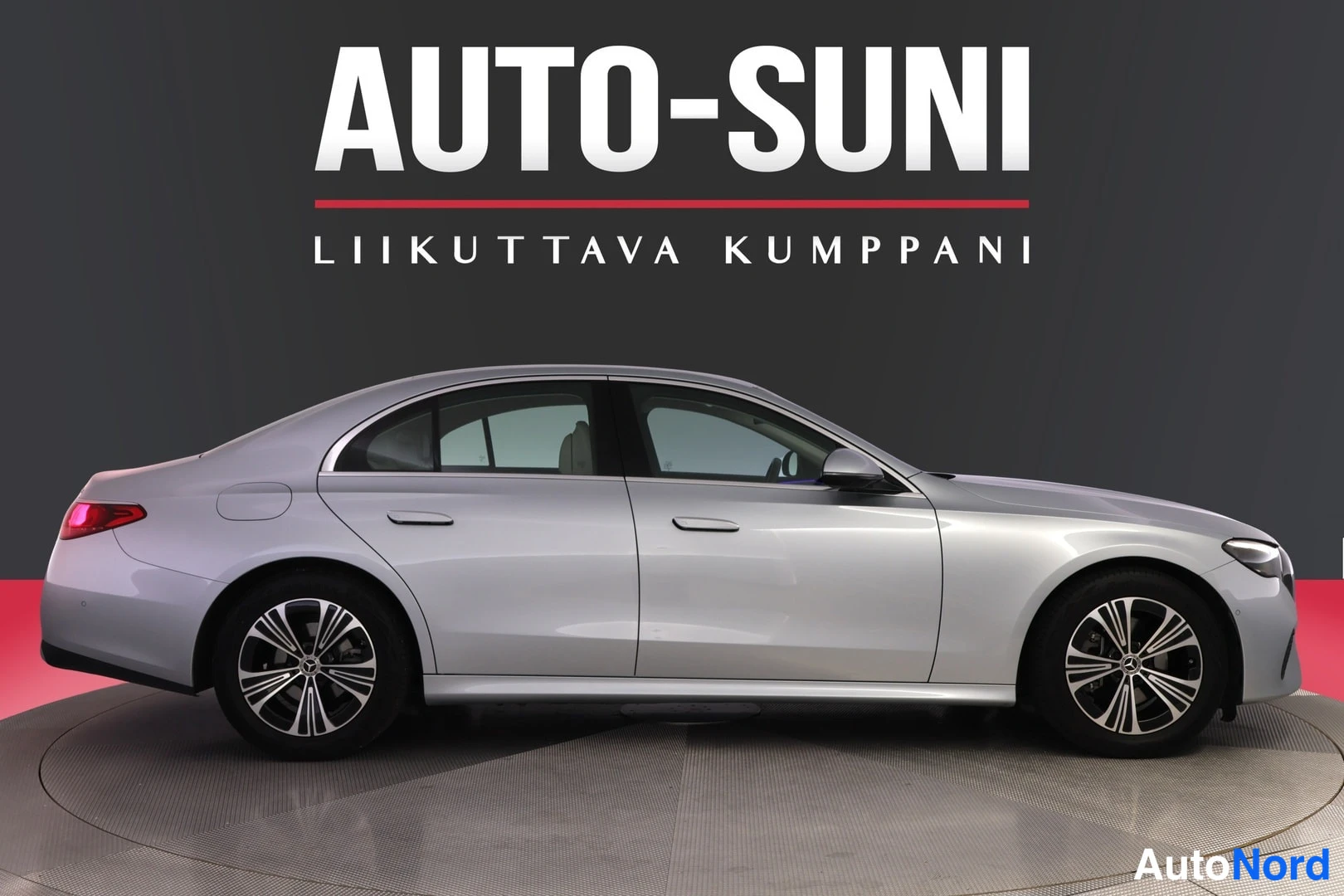 Etuviisto, nokka oikealle: Auton sivuprofiili oikealta etuviistöstä: hopeanvärinen sedan, nokka kuvan oikeassa reunassa, kevytmetallivanteet ja tummat ikkunat.