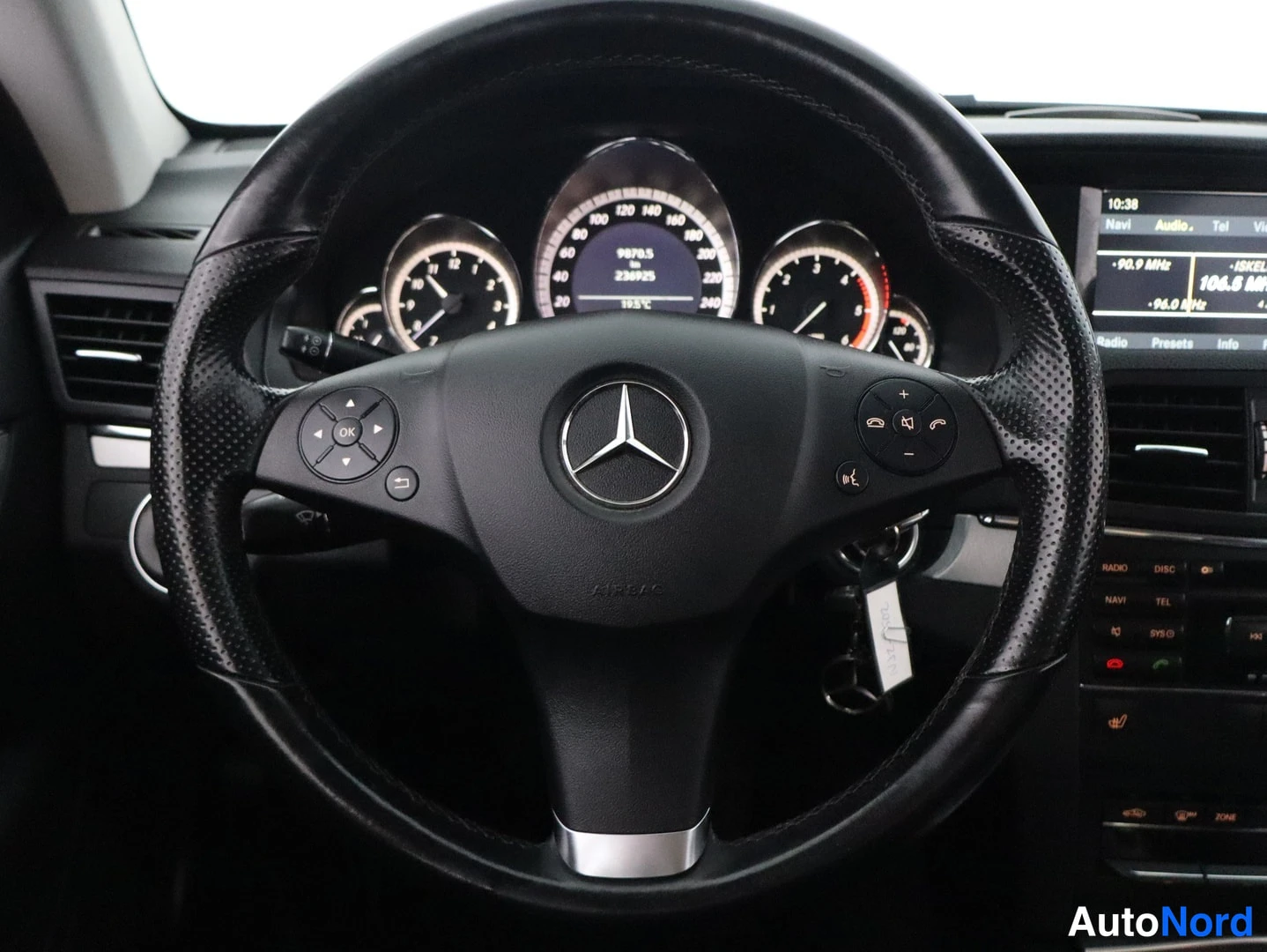 Muu: Ohjauspyörän ja kojetaulon näkymä: Mercedes-Benz-merkki pyörän keskiössä, taustalla mittaristo ja tiedotenäyttö.