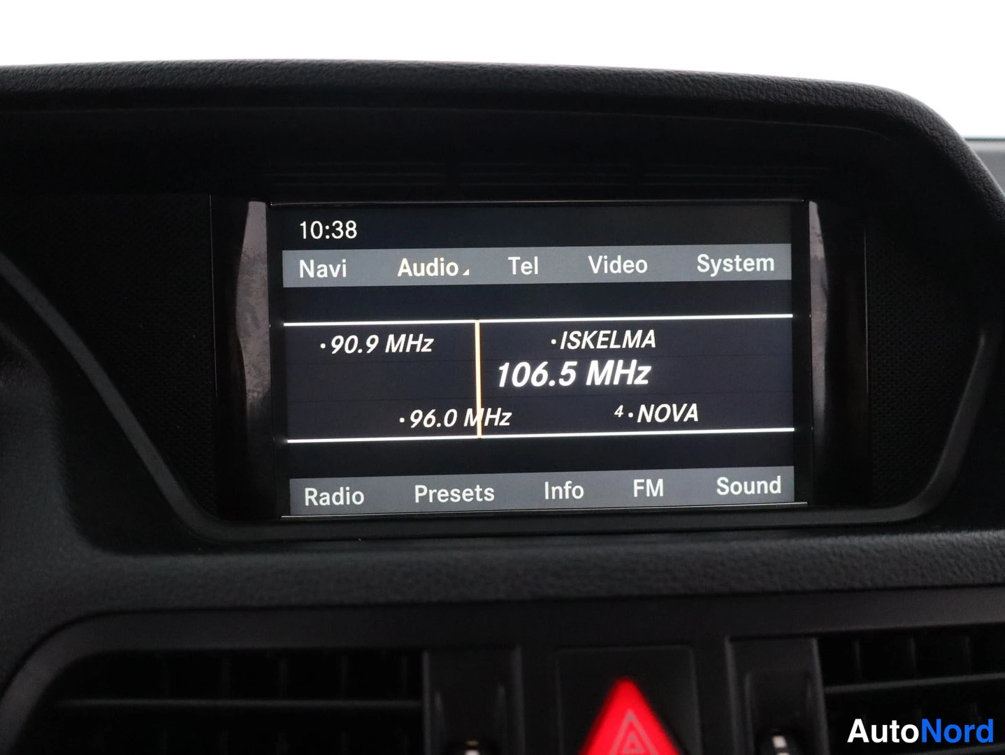 Muu: Mercedes-Benzin kojelaudan näyttö, jossa radioasetuksena ISKELMA 106.5 MHz ja valikot Navi, Audio, Tel, Video ja System.