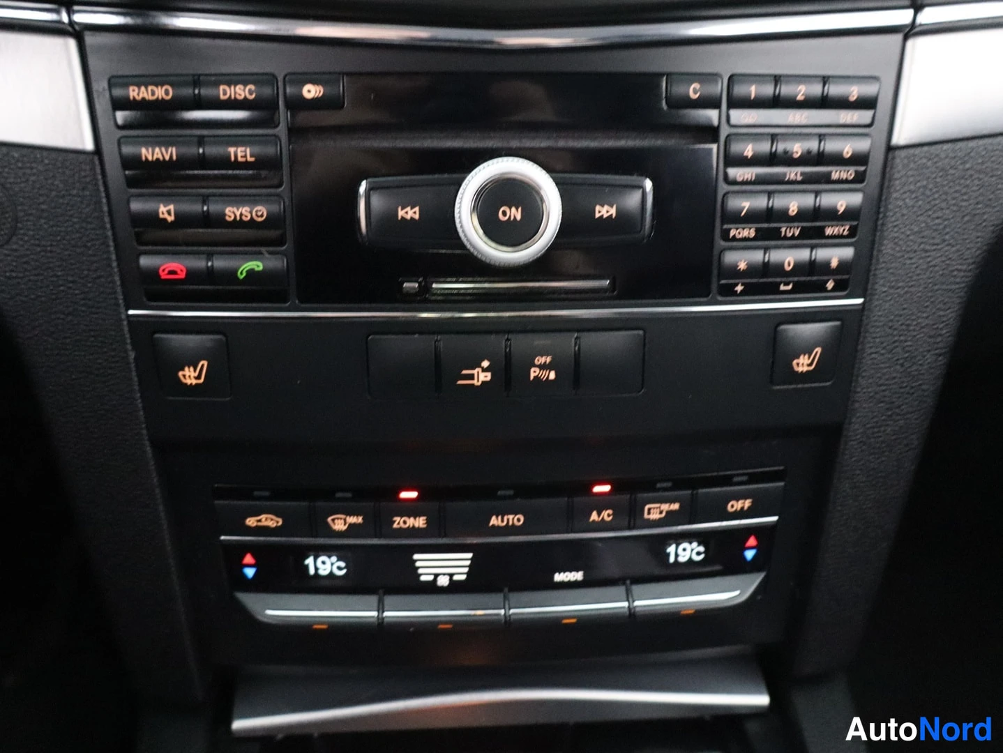 Muu: Mercedes-Benzin keskikonsolin painikkeet: radio, NAVI, TEL, numeronäppäimistö, istuimenlämmittimet, peruutuskamera ja ilmastointi 19 °C AUTO.
