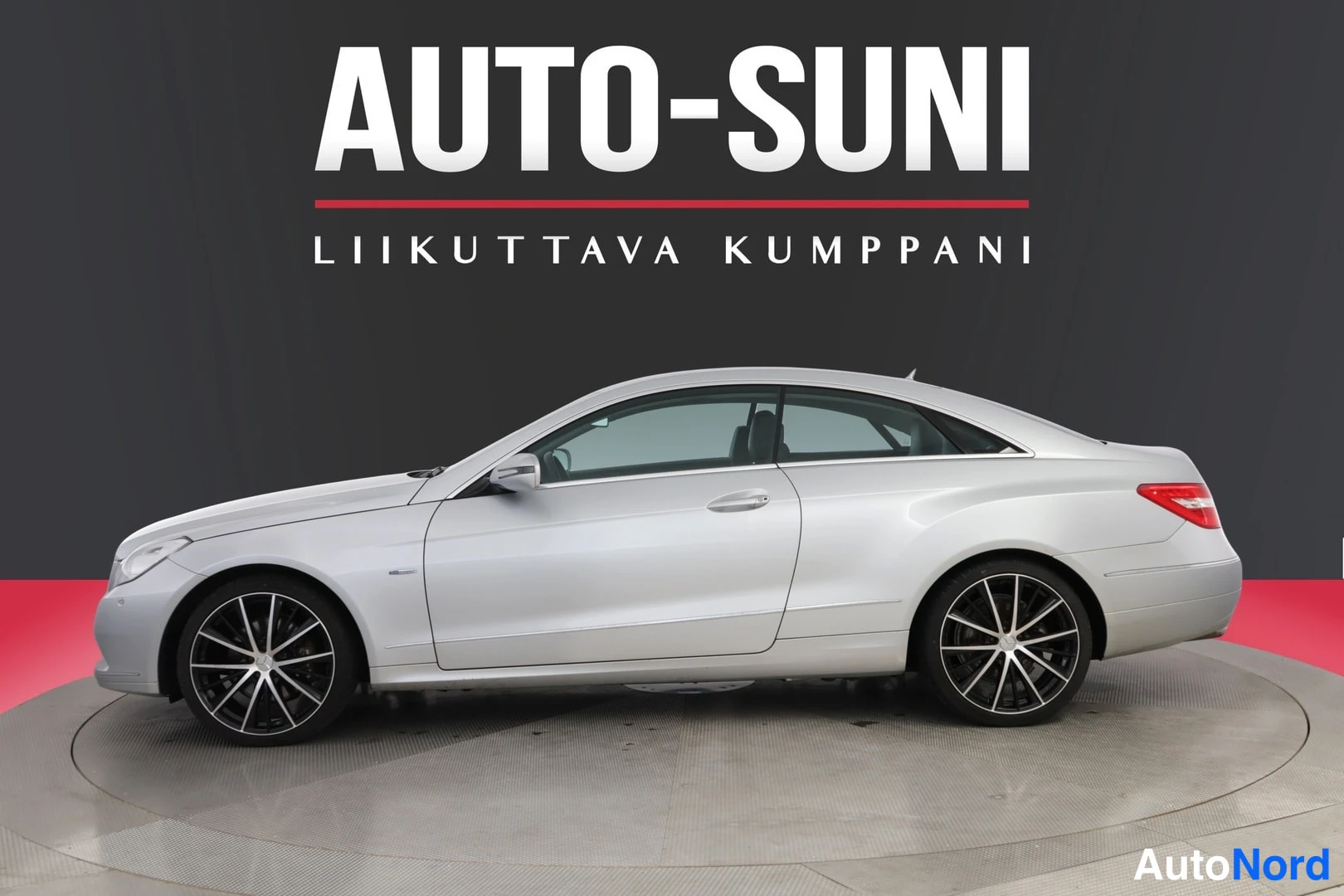 Sivulta: Hopeanvärisen coupé-auton sivukuva, oikea kylki näkyvissä tummat kevytmetallivanteet.