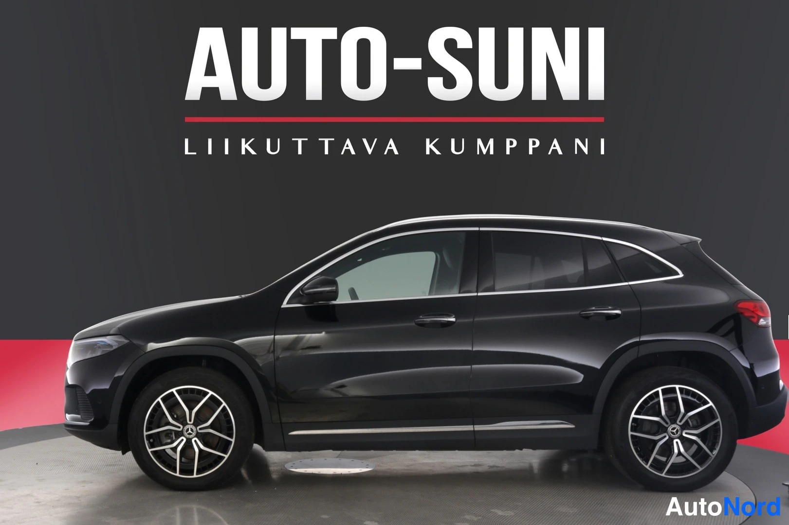 Sivulta: Autosalongin myymä musta Mercedes-Benz EQA -maasturin sivuprofiili, hopeat kevytmetallivanteet ja kattoeditori. Auton keula osoittaa vasemmalle.