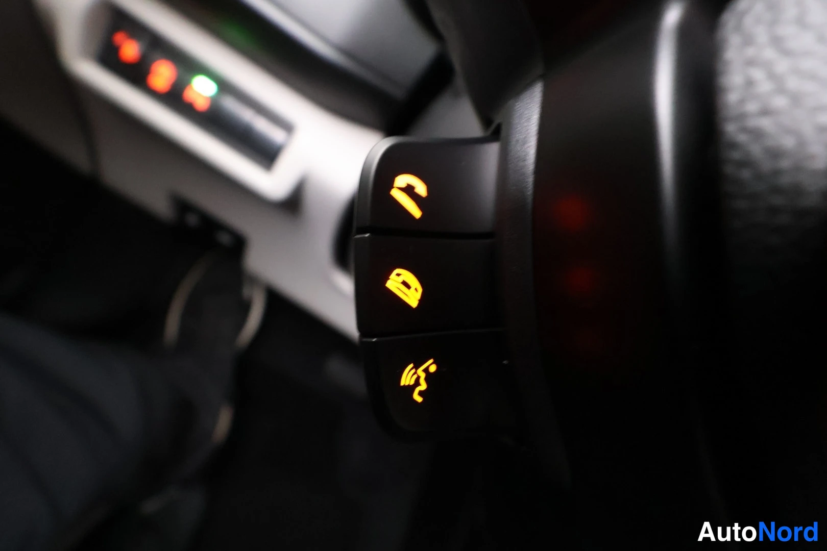 Muu: Suzuki Swift, kuva 1: Ohjauspyörän puhelin- ja hälytysnäppäimet valaistuina, tausta epätarkka.