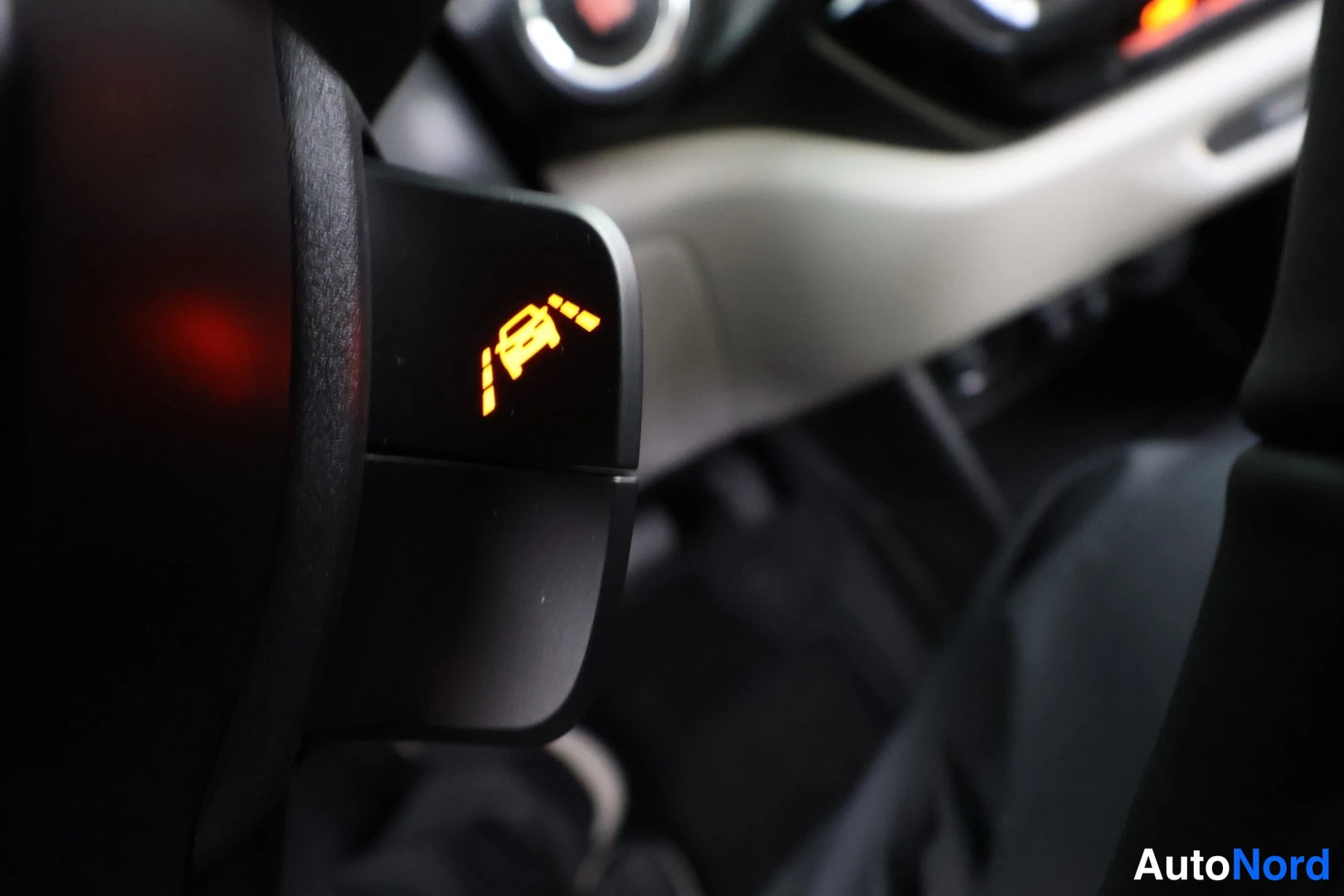 Muu: Suzuki Swift, kuva 3: Ohjauspyörän varressa oranssi kaistaltapoistumisvaroituksen symboli, tausta epätarkka.