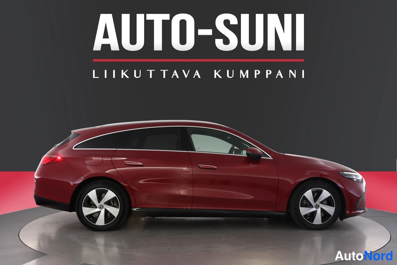 Sivulta: Tummanpunainen Mercedes-Benz CLA -farmari täysin sivulta, molemmat pyörät profiilissa, studiotausta ja AUTOSUNI-banneri.