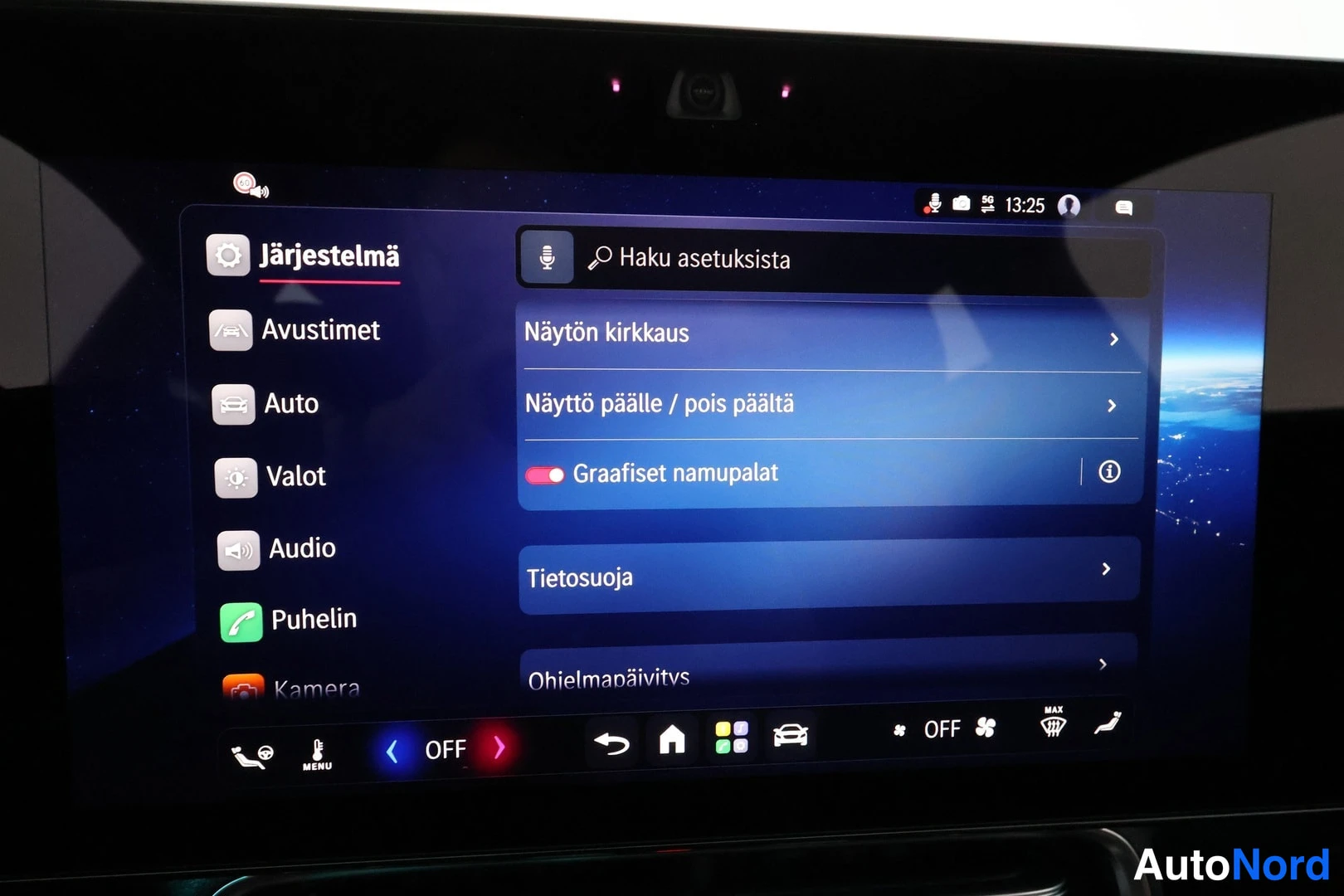 Yksityiskohta: Auton infotainment-näytön Järjestelmä-asetussivu, jossa valikossa Avustimet, Auto, Valot, Audio, Puhelin ja Kamera sekä asetukset Näytön kirkkuus, Näyttö päälle