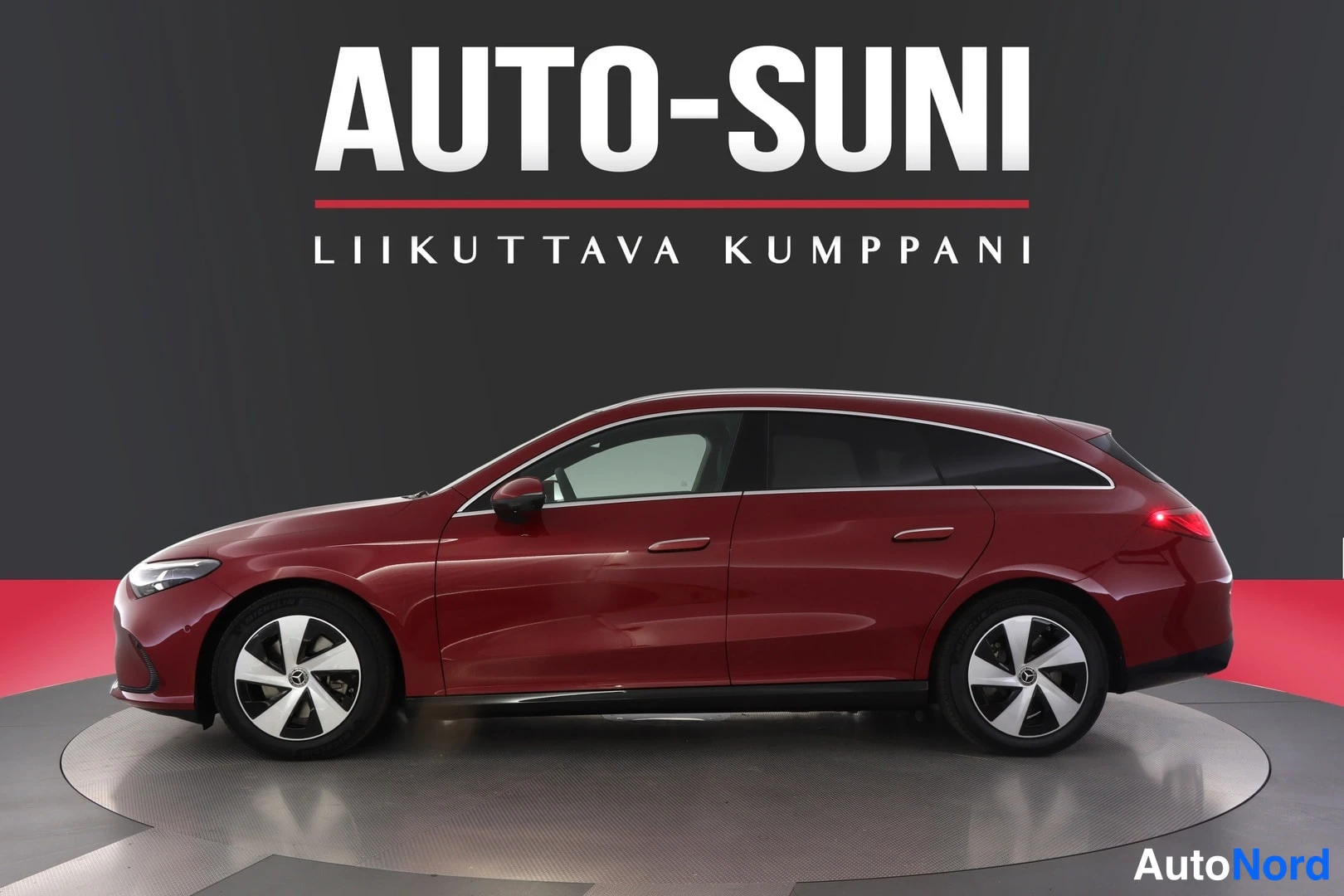 Sivulta: Sivunäkymä punaisesta henkilöautosta, jossa on kiiltävät väriset ja peiliin heijastuva alusta.