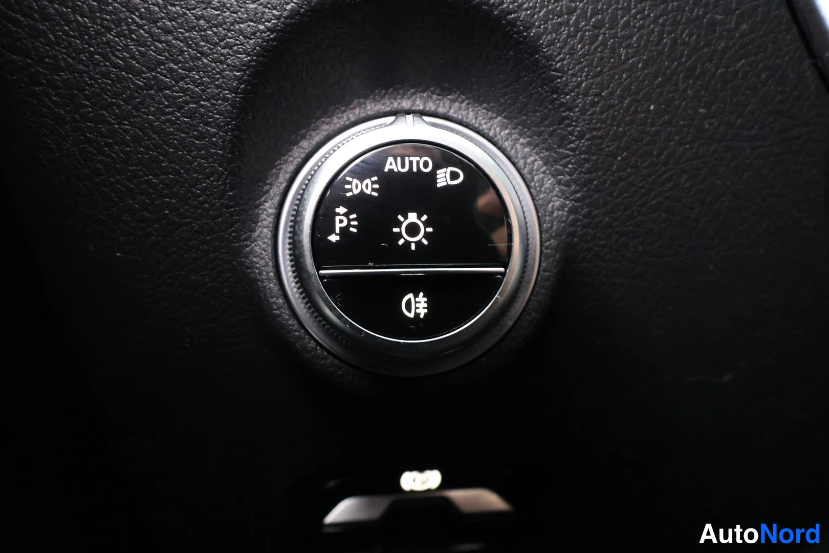 Muu: Musta valaistuskytkin kojelaudassa, jossa AUTO-asento ja symbolit parkkivaloille, välkytyksille, sumuvaloille ja kirkasvaloille