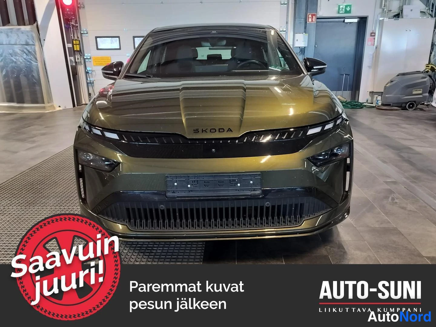 Edestä: Etunäkymä tummanvihreästä Skoda Enyaq Coupé -autosta korjaamotilassa, etusäleikkö ja sumuvalot.
