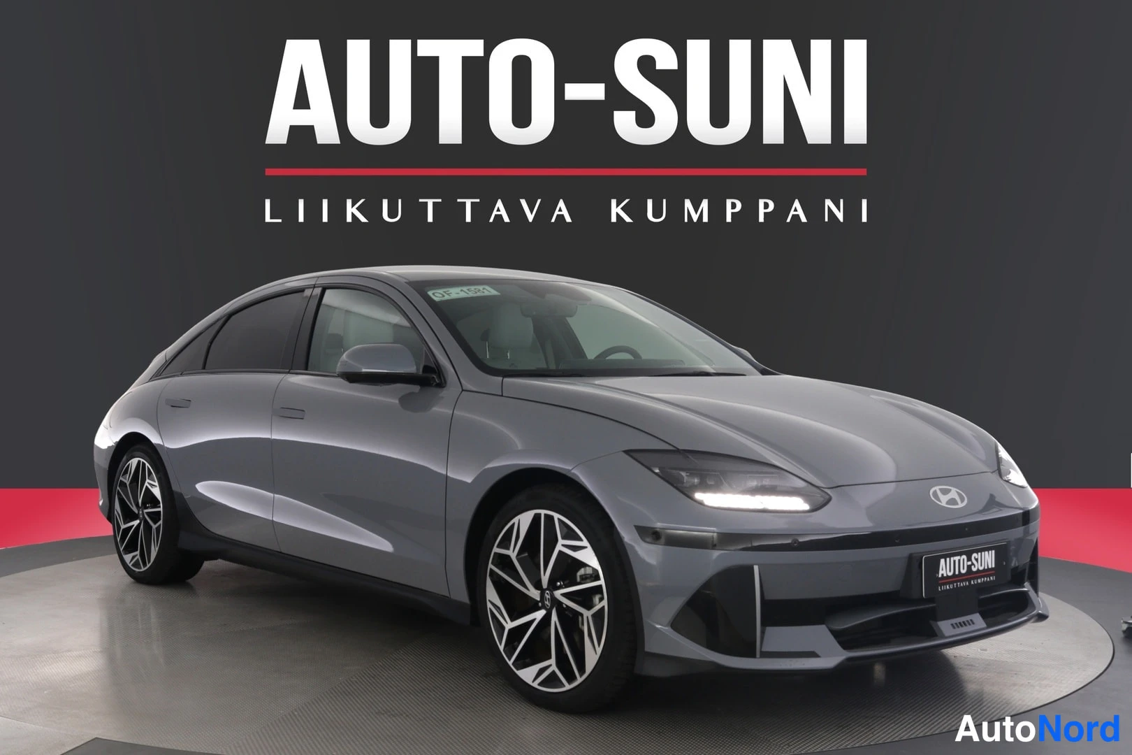Etuviisto, nokka oikealle: Hopeanharmaan Hyundai IONIQ 6:n etukulmanäkymä, etugrilli ja ajovalot näkyvät oikealla, kylki ja monihaaravannastettu alumiinivanne vasemmalla.
