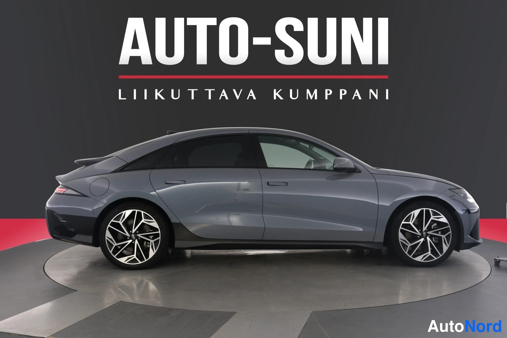 Sivulta: Hopeanharmaan Hyundai IONIQ 6:n sivunäkymä, koko kylki ja molemmat pyörät kuvassa, tummat ikkunalasit.