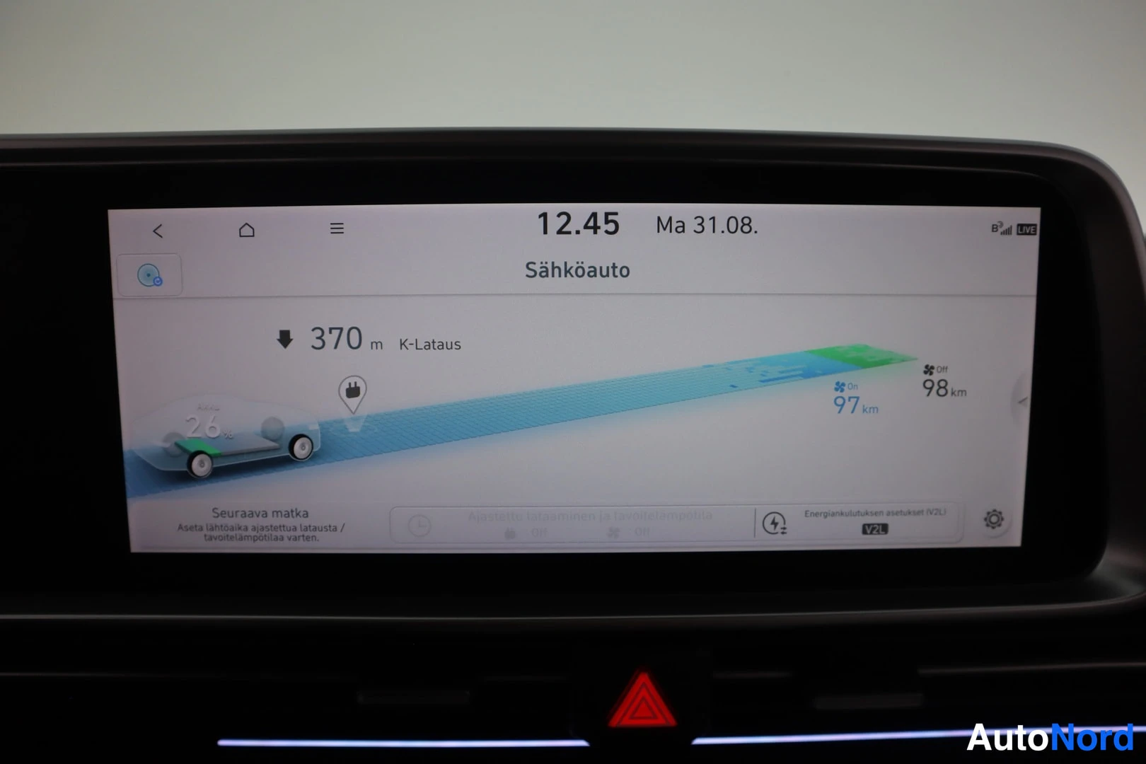 Muu: Auton sähköauto-näyttö näyttää toimintamatkatiedot: 26 % lataus, 97 km kantama, 98 km ilmastoinnin pois, ja seuraava lataus K-Lataus 370 m päässä.