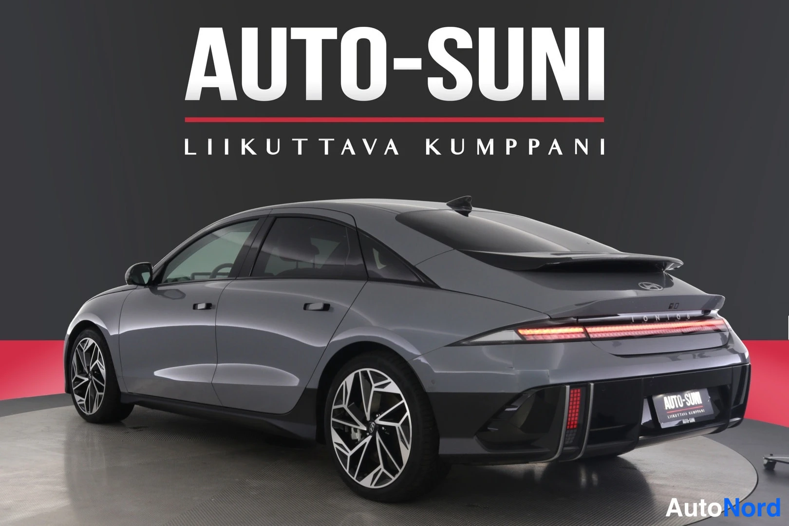 Takaviisto: Hopeanharmaan Hyundai IONIQ 6:n takakulmanäkymä oikealta, spoileri kattaa takalasin, takavalot ja musta alakolmio näkyvät.