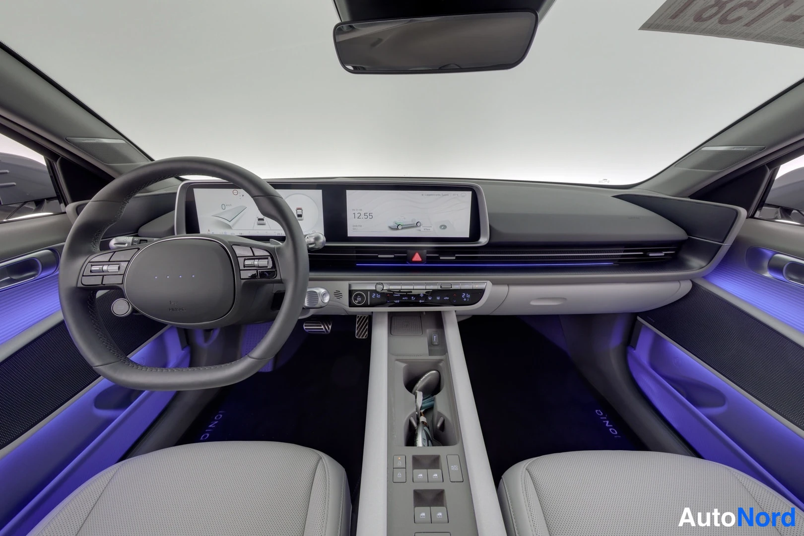 Muu: Hyundai IONIQ 6:n ohjaamo, kaksi näyttöä, sininen tunnelmavalaistus, vaaleat penkit, vasemmanpuoleinen ohjauspyörä