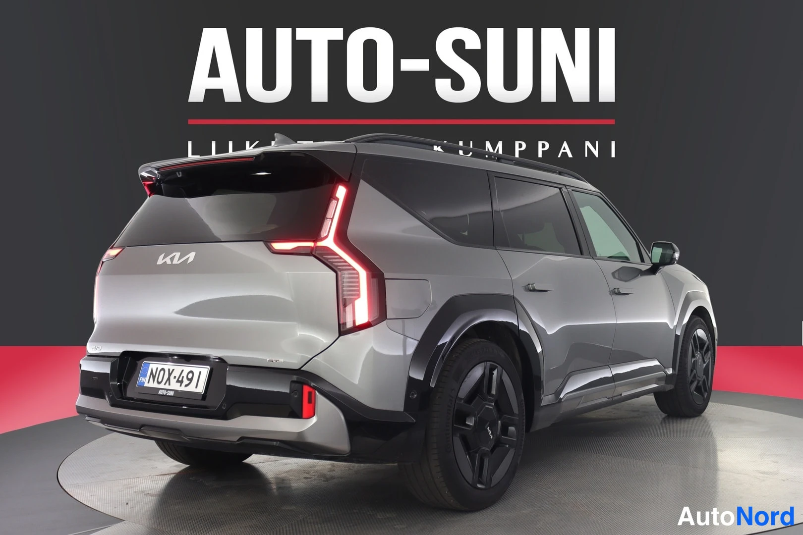 Takaviisto: Hopea Kia EV9 suoraan takaa viistosti vasemmalta, valot syttyneinä, kilpi, korirakenteessa mustia muoviosia.