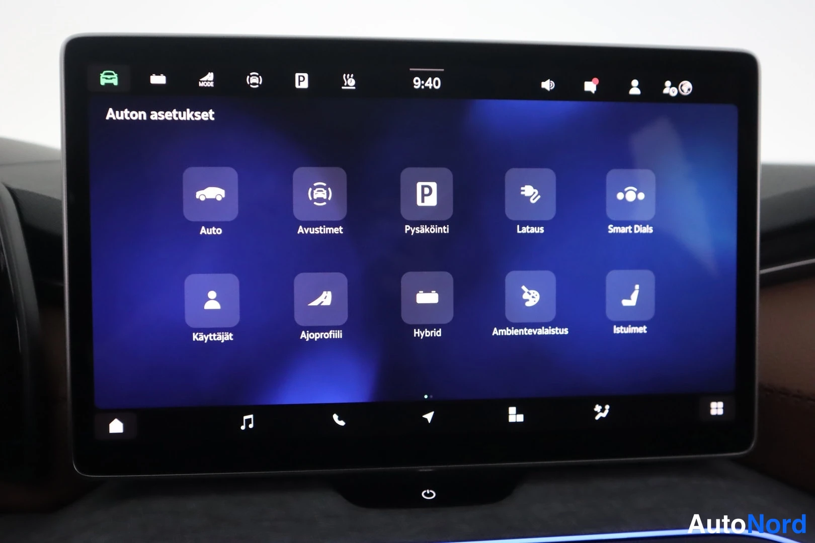 Muu: Auton infotainment-näyttö, jossa 'Auton asetukset' -valikko ruudukolla: Auto, Avustimet, Pysäköinti, Lataus, Smart Dials, Käyttäjät, Ajoprofiili, Hybrid, Ambien