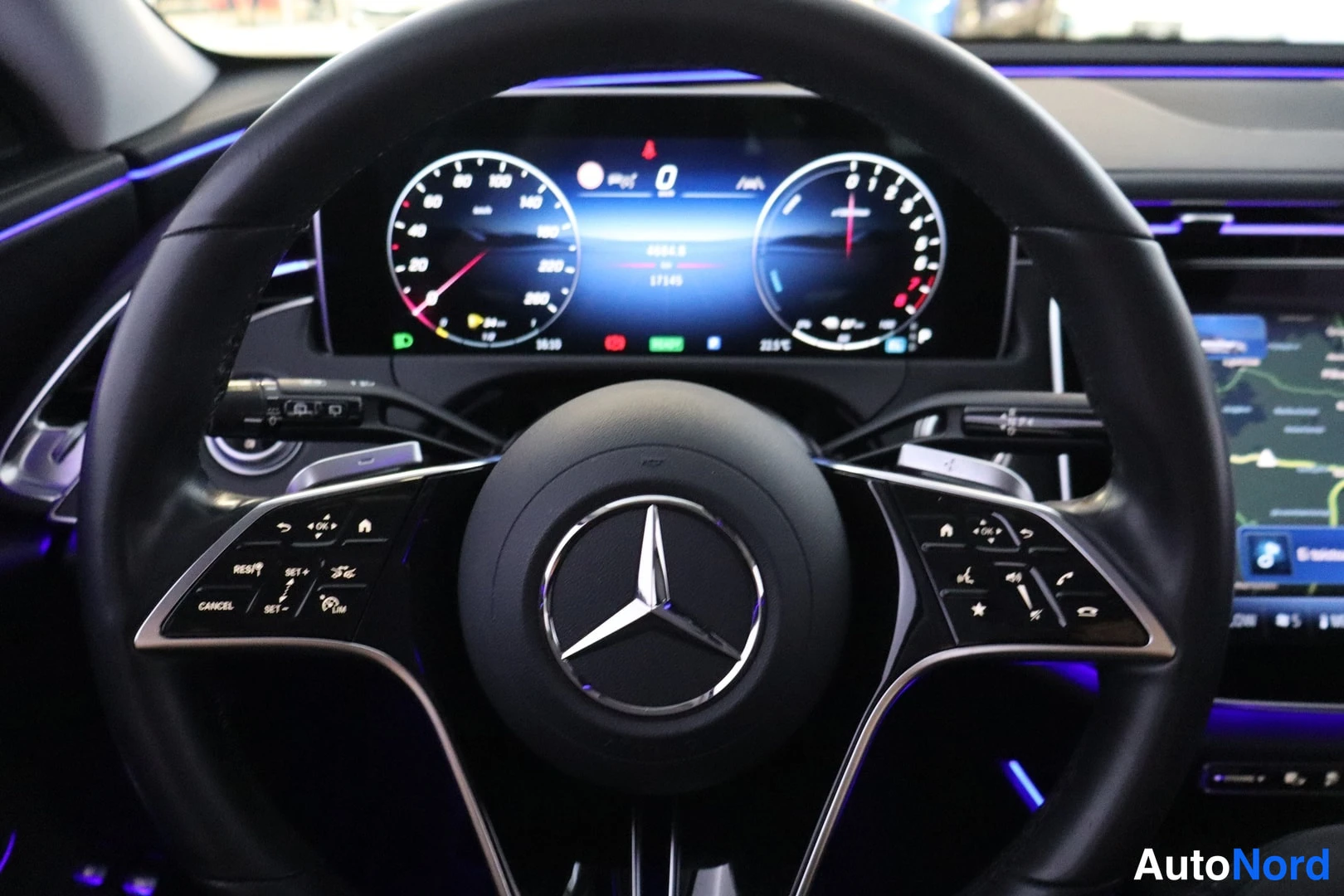 Sivulta: Mercedes-Benzin ohjauspyörä ja instrumentisto: digitaalinäytöt,viistot ratnapainikkeet ja viisto taksamittari,kriittinen kartta näkyy keskinäisessä näytössä.