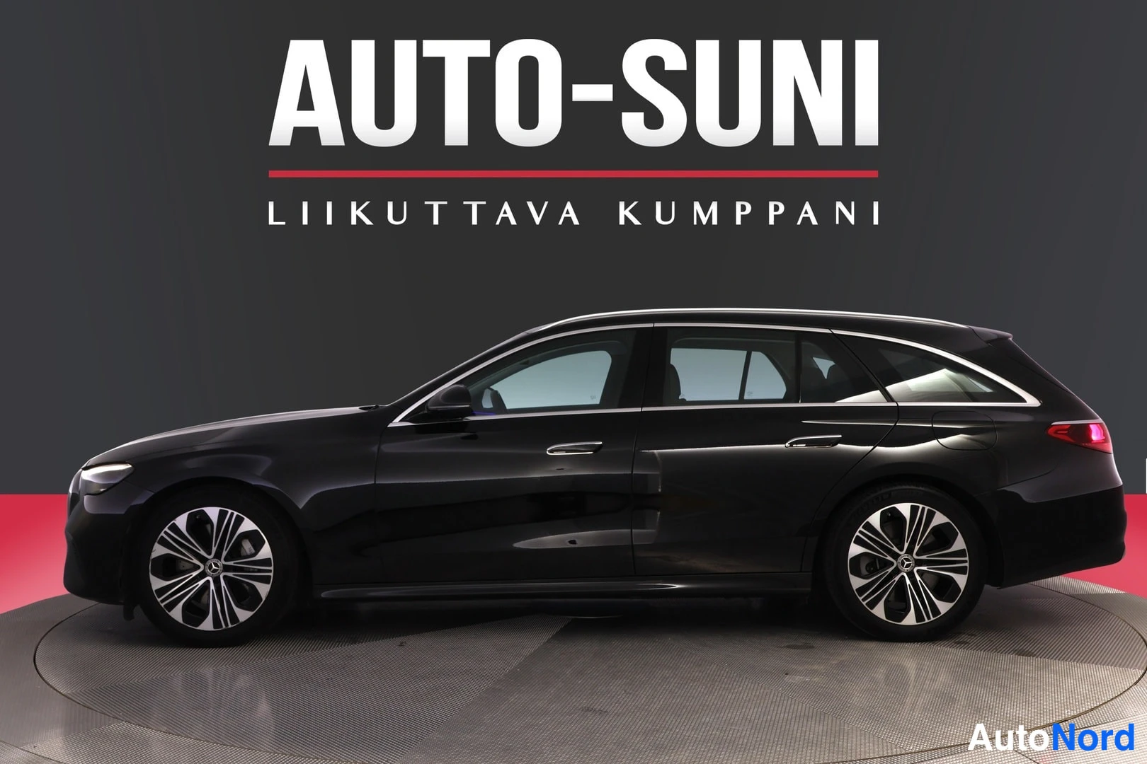 Sivulta: Mustan Mercedes-Benz-farmarin sivuprofiili, oikea kylki kuvattuna studioympäristössä AUTO-SUNI-logon alla.