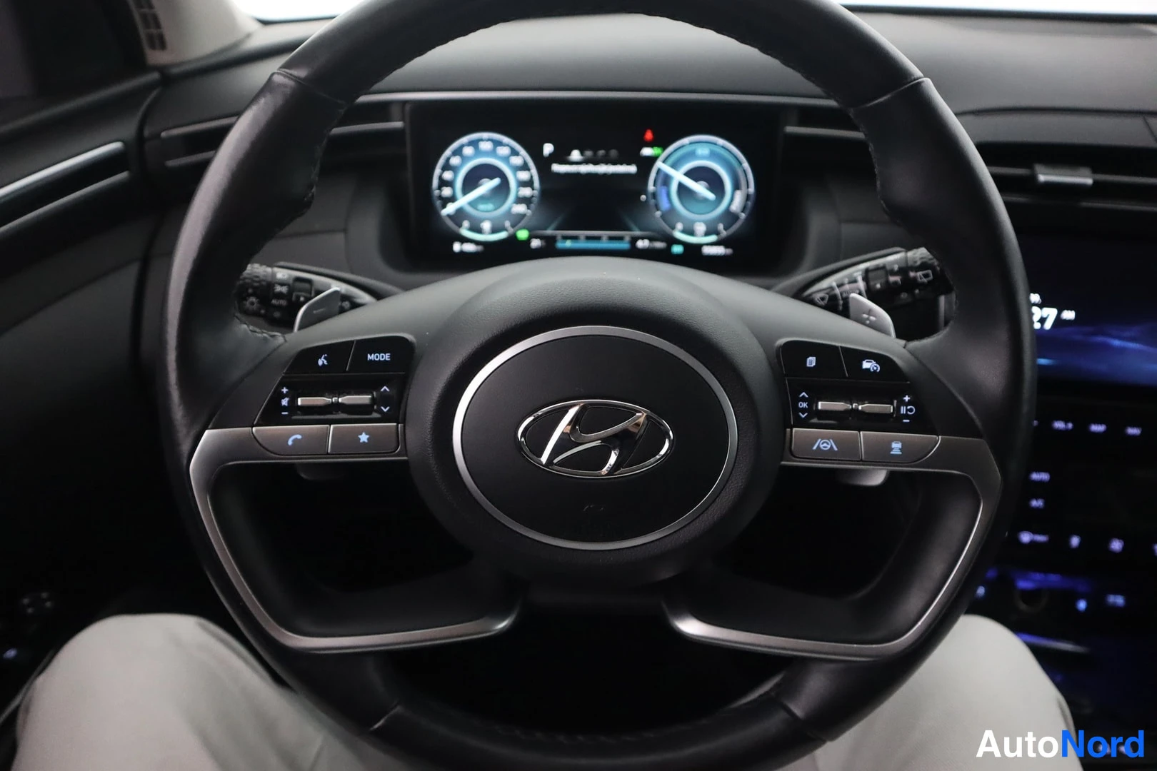 Muu: Hyundai Tucsonin ohjauspyörä Hyundai-logolla, monitoiminapit (mm. MODE, OK, puhelin) ja digitaalinen mittaristo ratin takana.