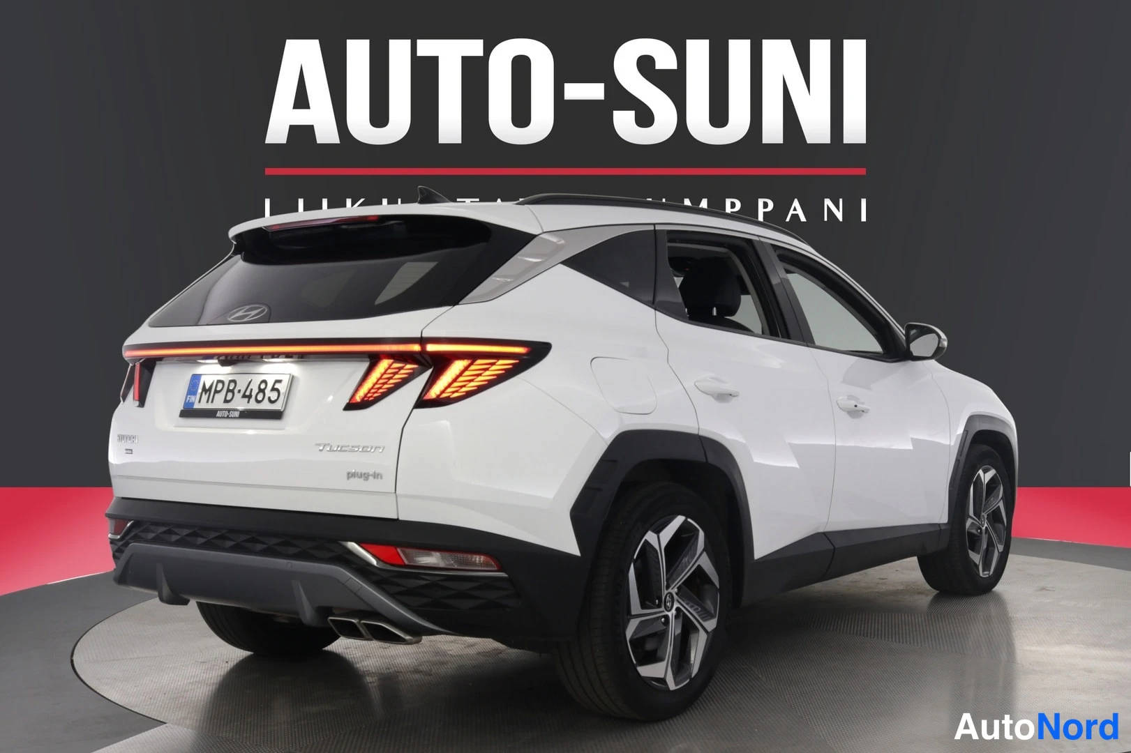Takaviisto: Valkoinen Hyundai Tucson takaviistosta kuvattuna, jälkivalot päällä ja rekisterikilpi.