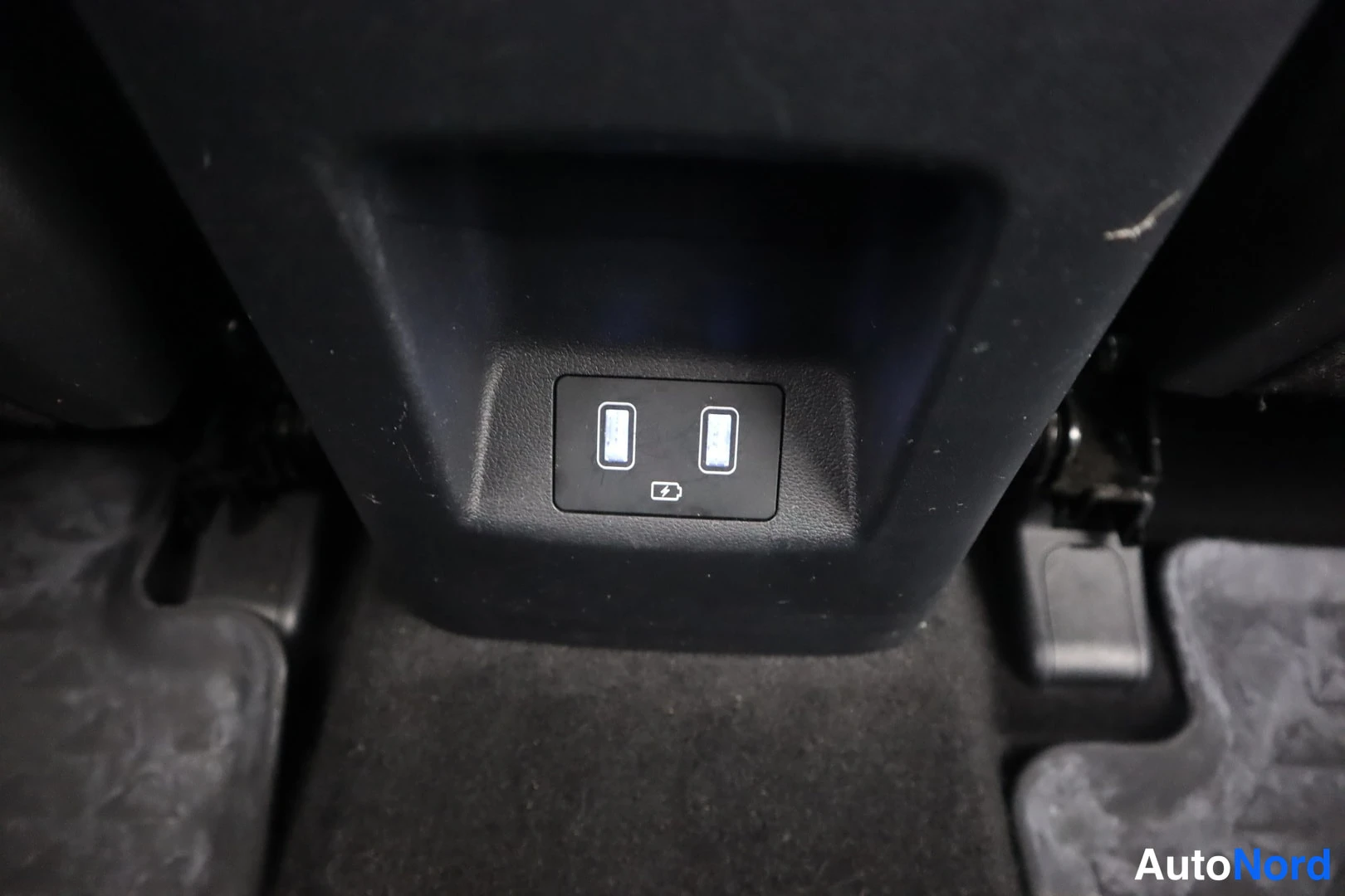 Yksityiskohta: Kaksi USB-porttia keskikonsolin takaosassa, ympäristö mustaa muovia.