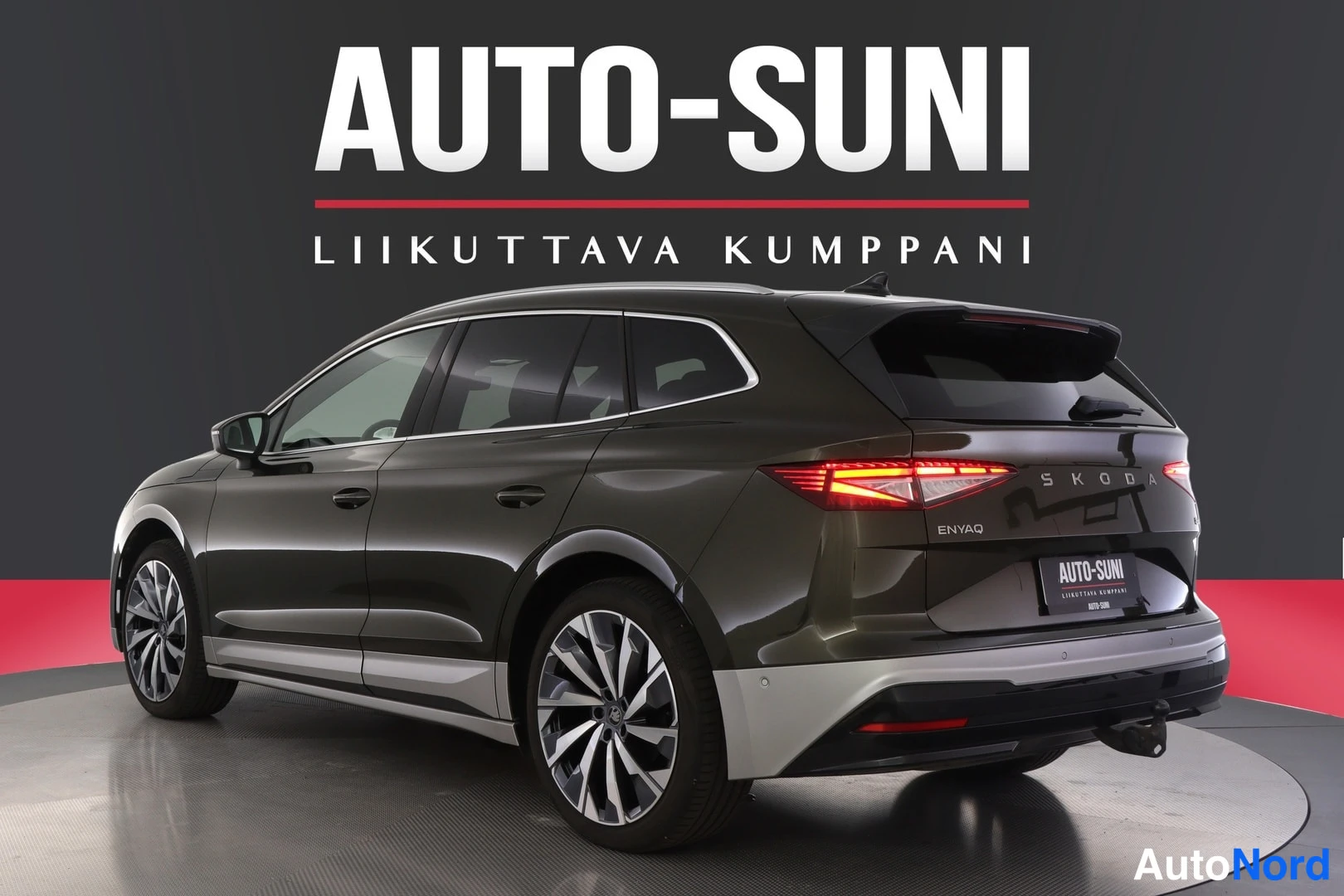 Takaviisto: Auto-Suni-studio: Skoda Enyaq 85x takaviistossa vasemmalta, tumman oliivinruskea kori ja hopeiset alakankaat