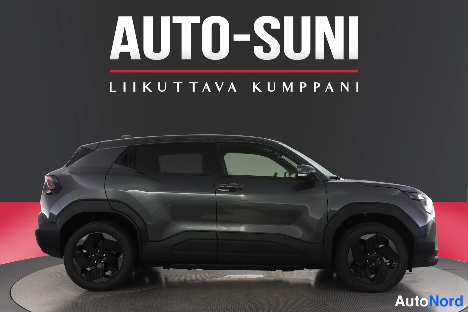 Sivulta: Tummanharmaan henkilöauton sivuprofiili studio-ympäristössä.