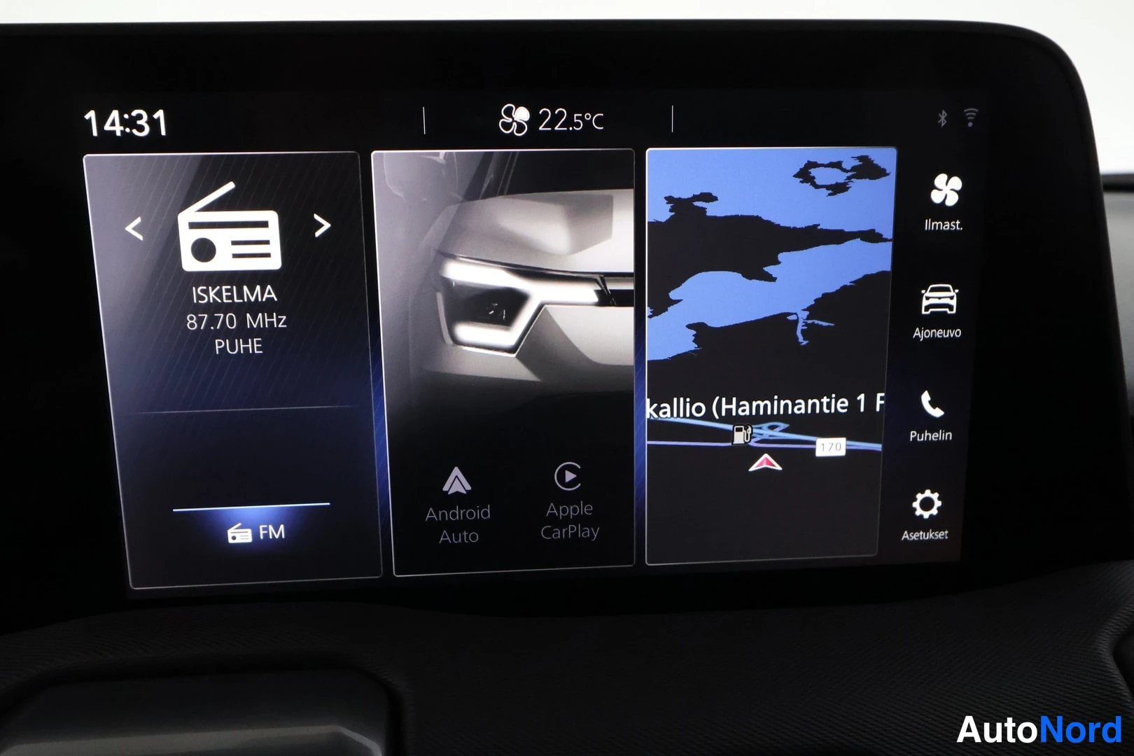 Muu: Auton infotainment-näyttö: radio (ISKELMA 87.70 MHz), Android Auto- ja Apple CarPlay-kuvakkeet, kartta ja valikot kuten Ilmast. ja Ajoneuvo.