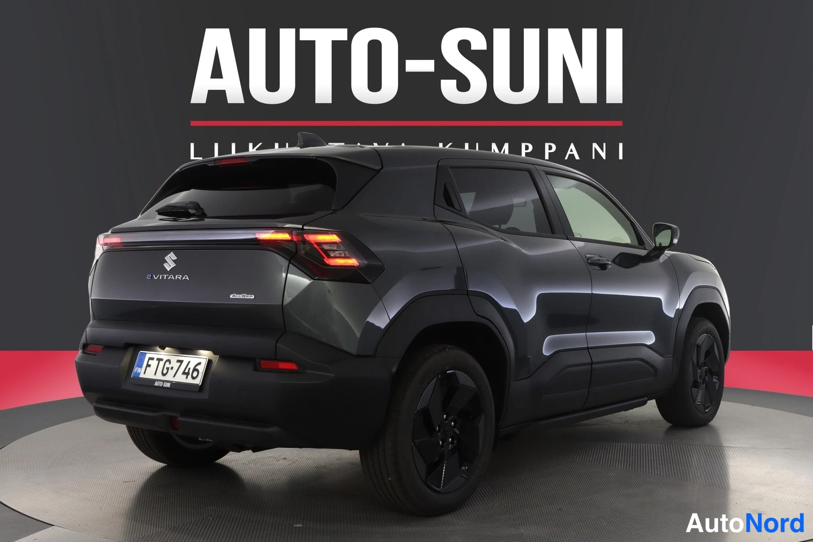 Takaviisto: Tummanharmaa henkilöauto takaviistosta, rekisteritunnus, takaluukussa e VITARA -teksti.