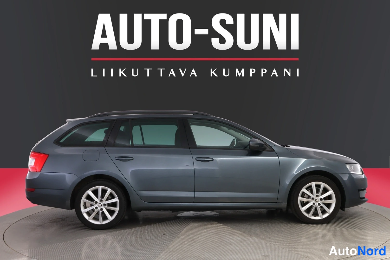 Sivulta: Sinertävän harmaa Skoda Octavia -farmari sivulta oikealta.