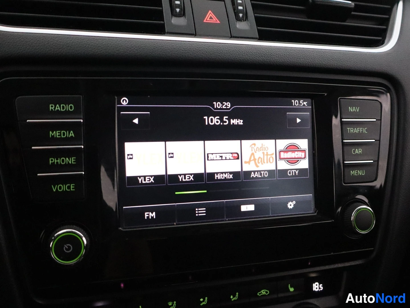 Muu: Auton infotainment-järjestelmä, näytöllä radio 106.5 MHz ja NAV-painike.