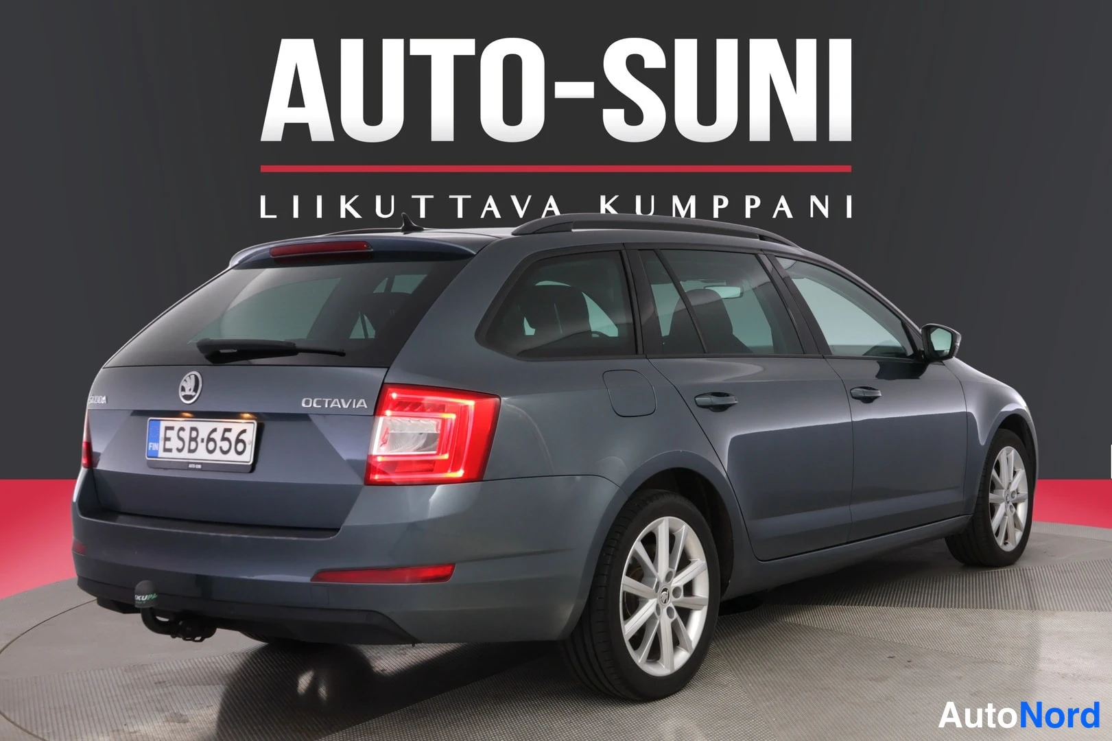 Takaviisto: Sinertävän harmaa Skoda Octavia -farmari kolmesta neljäsosasta takaa vasemmalta, rekisterikilpi, OCTAVIA-teksti takaluukussa.