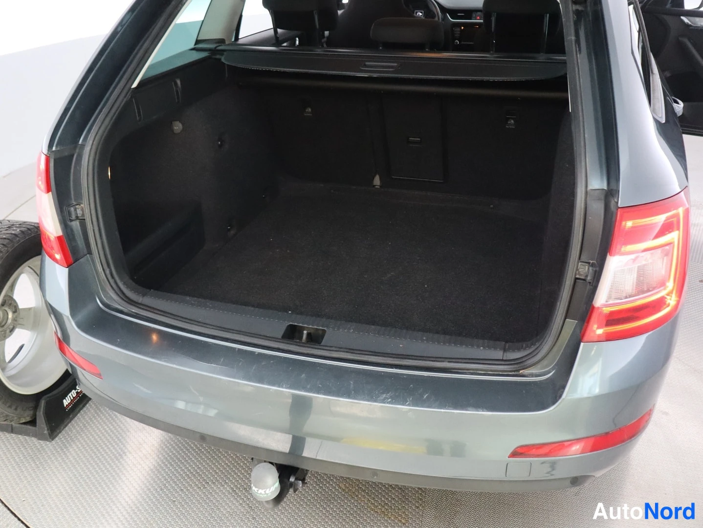 Takaa: Avoimella takaluukulla kuvattu auto takaapäin; tyhjä, tummaverhoiltu tavaratila ja vetokouku kaula takapuskurin alla. Vasemmassa reunassa talvirenkaalla varuste