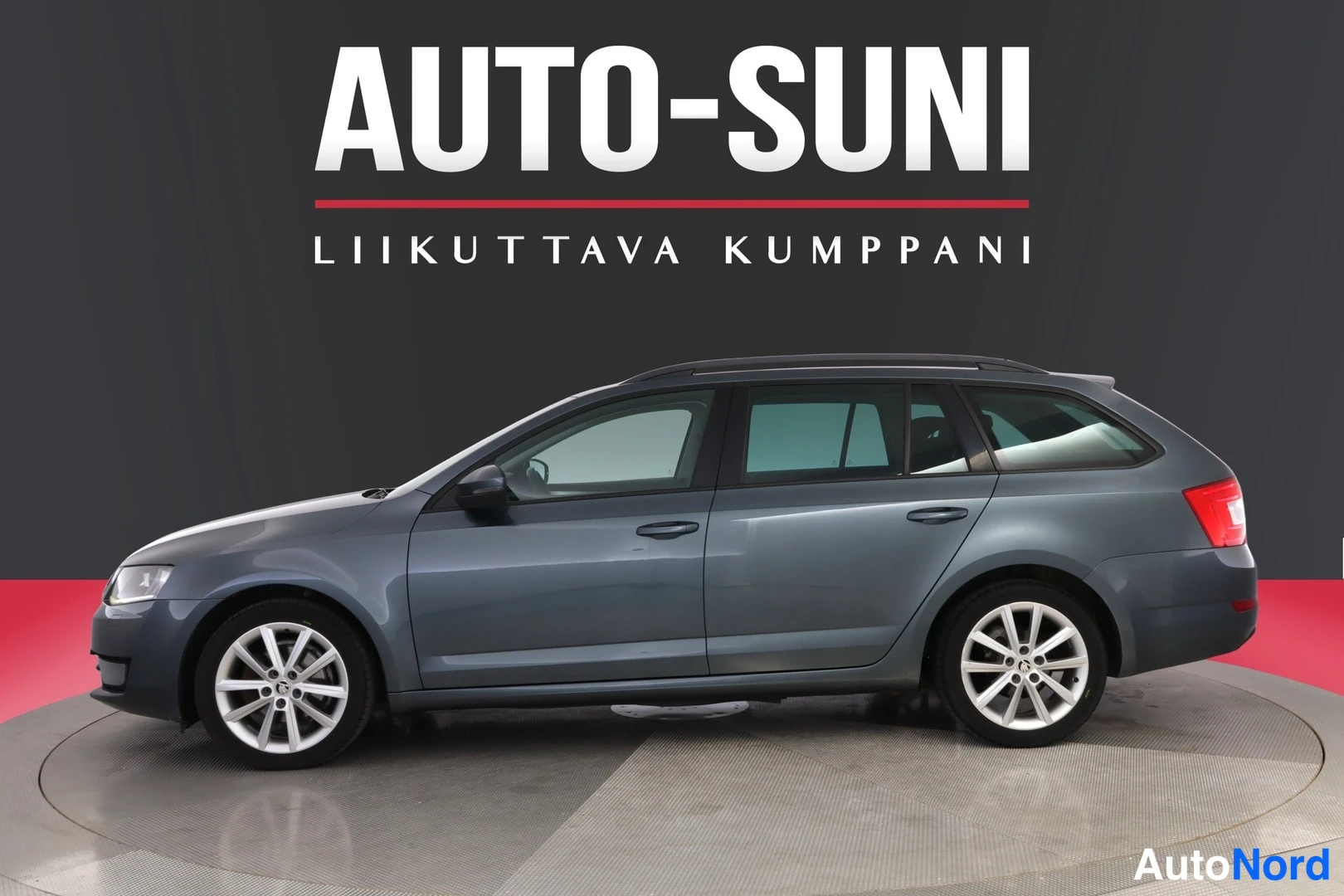 Sivulta: Auton kylki ja keulaa vinosävyttömästi vasemmalta; harmaa farmariauto studiossa.