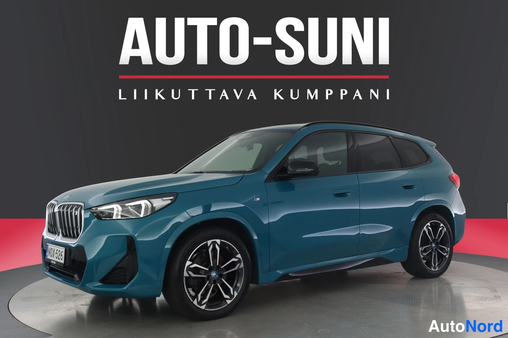 Etuviisto, nokka vasemmalle: Sininen BMW-henkilöauto kulmassa etuosa vasemmalle, kokonaisuudessaan esillä studiovaalealla taustalla.