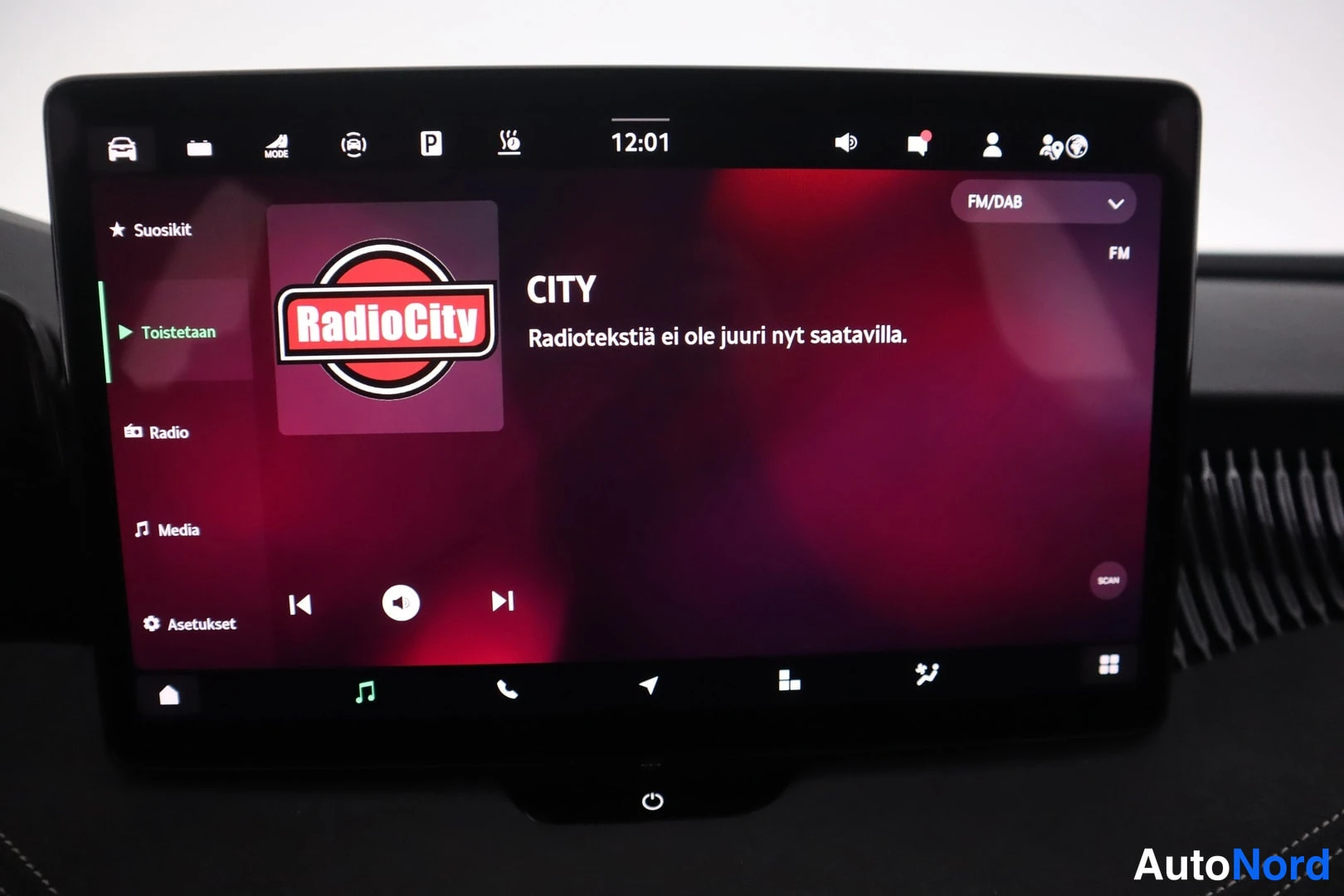 Yksityiskohta: Auton kojelaudan infotainment-näyttö, jossa toistetaan RadioCity-FM-radiokanavaa; ruudulla lukee 'CITY' ja 'Radiotekstiä ei ole juuri nyt saatavilla', kellonaik