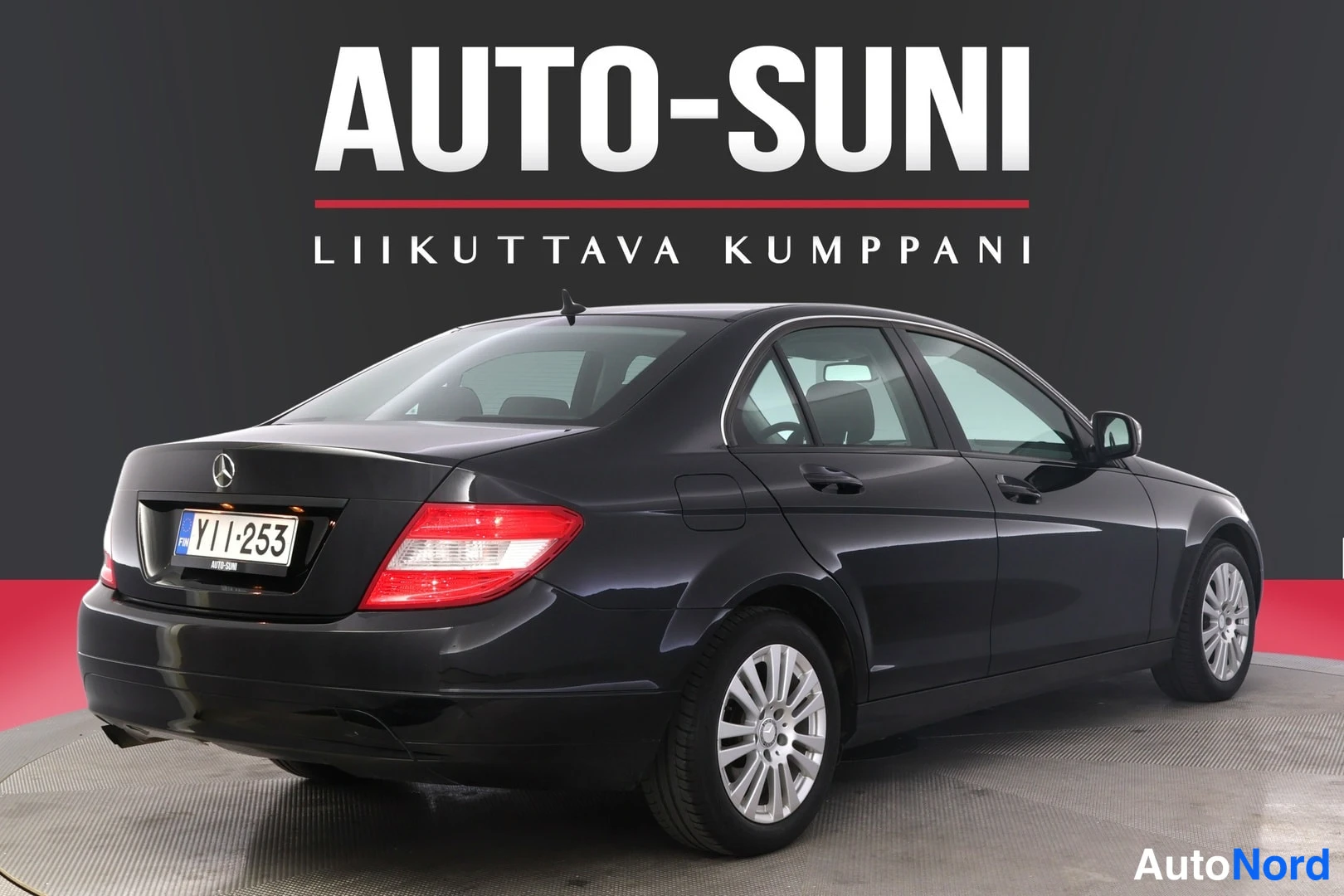 Takaviisto: Mustan Mercedes-Benz C 2008 -henkilöauton takakulmakuva, rekisterikilpi YI I-253, studiotauustaa vasten.