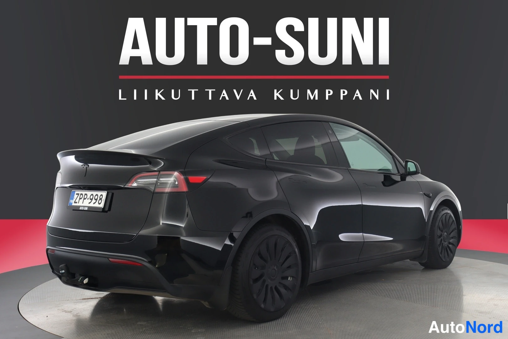 Takaviisto: Musta Tesla Model Y takaosto-kulmasta, rekisteritunnus, takahaara ja mustat vanteet nähtävissä.