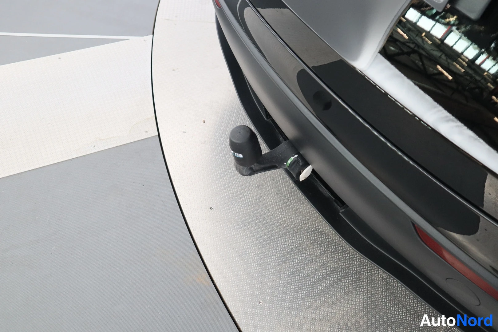 Takaa: Lähikuva auton takapuskasta, jossa on irrotettava vetokoulu. Auto seisoo kääntölavalla.