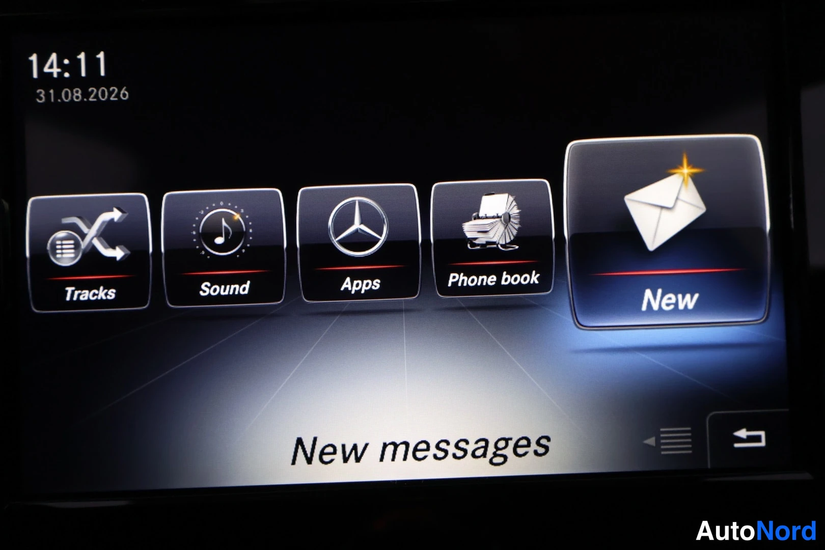 Muu: Mercedes-Benzin infotainment-näytön infotainment-näytön kuva: näytöllä näkyy 14:11, 31.08.2026 ja valikko Tracks, Sound, Apps, Phone book, New, tekstinä New mes