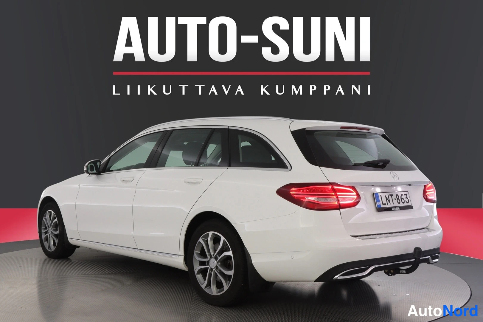 Takaviisto: Valkoisen Mercedes-Benz C farmarin takakolmisivukuva oikealta, rekisteritunnus, vetokoukku näkyvissä.