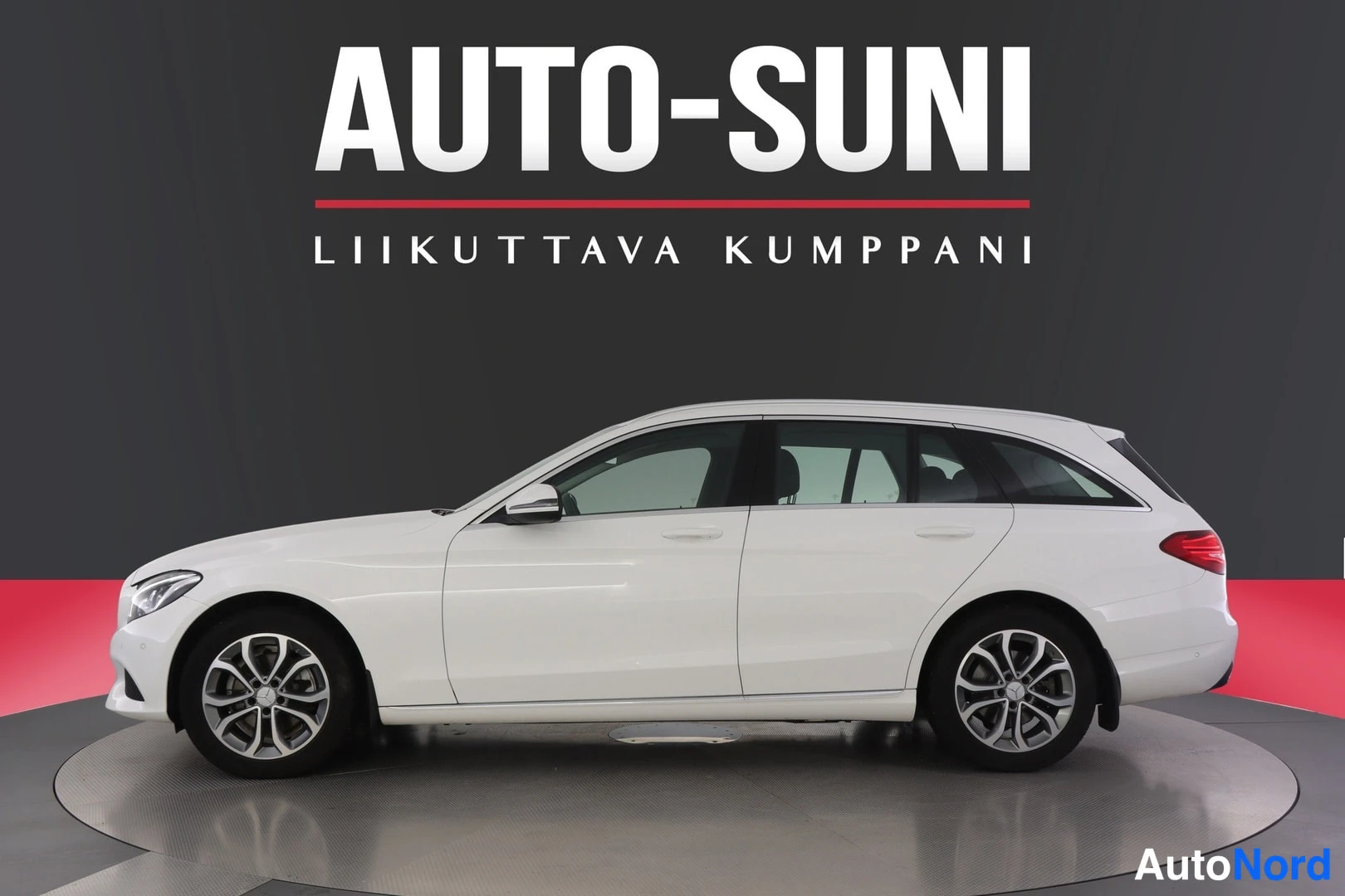 Sivulta: Mercedes-Benz farmari sivuprofiilissa, valokuvattu myyntihallissa mustaa taustaa vasten