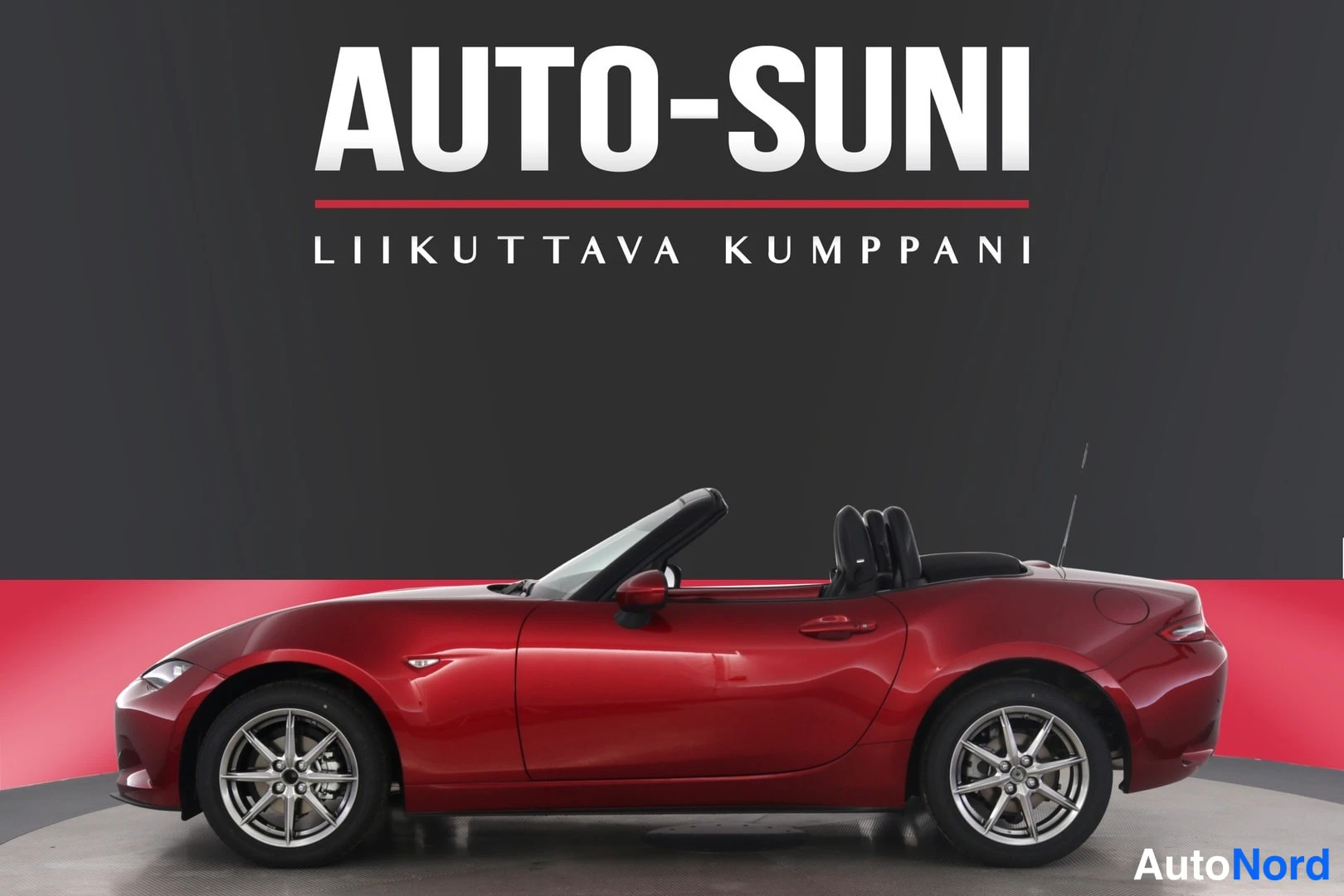 Sivulta: Punainen avokattoinen urheiluauto sivulta, kaksi istuinta ja takamatot näkyvät.