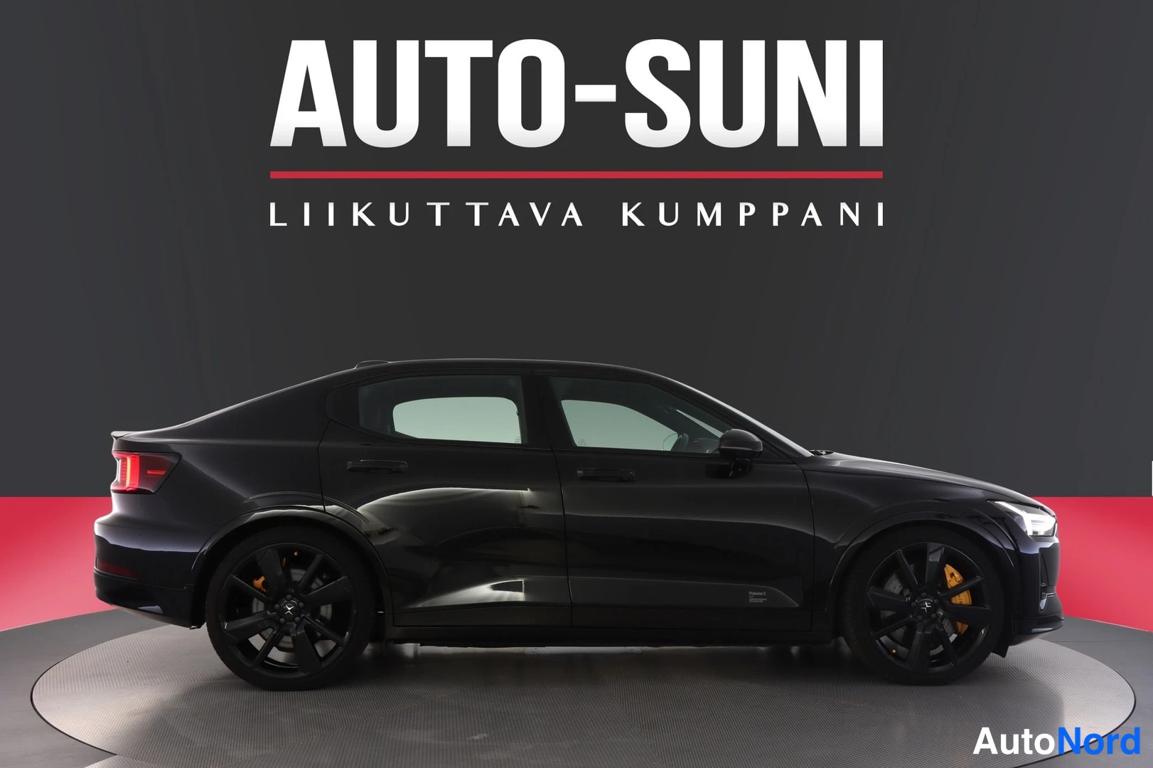 Etuviisto, nokka oikealle: Autosuni-studio: mustan sedanin sivuprofiili, oranssit jarrusatulat molemmissa pyörissä.