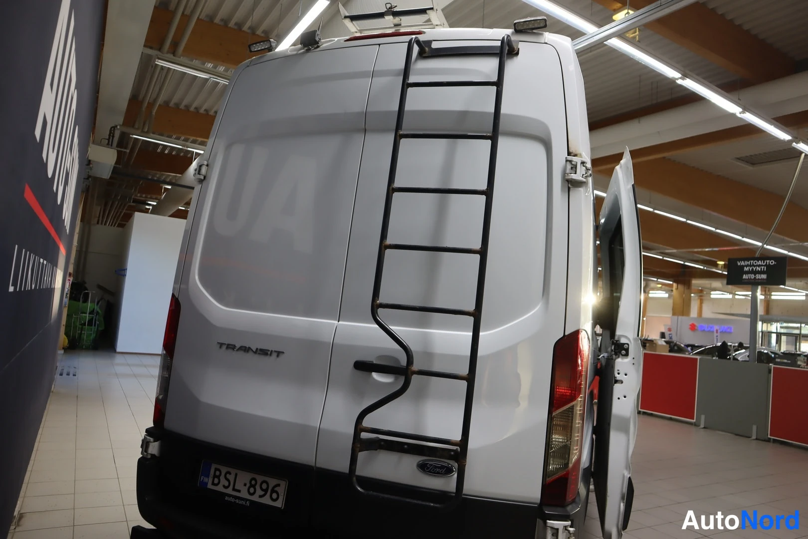 Takaa: Ford Transitin takaosa katolikkineen; rekisterikilpi ja Transit-teksti takaluukussa.