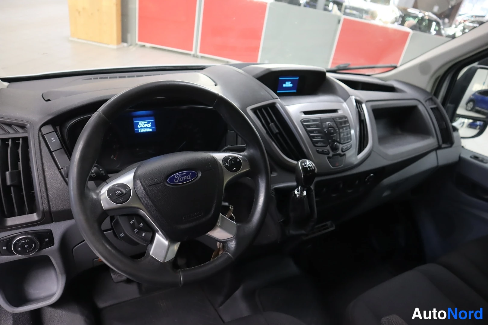 Yksityiskohta: Auton sisätilat: ohjauspyörä Ford-logolla, kojelauta, manuaalivaihteen keila ja keskikonsoli näkyvät.